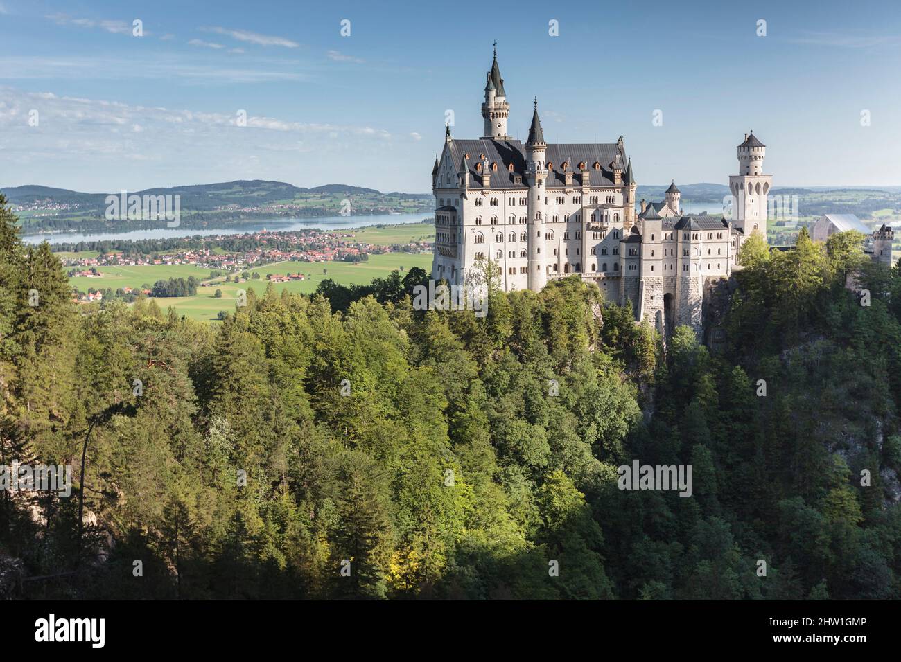 Allemagne, Bavière, haute-Bavière, Allg?u, Schwangau, Château de Neuschwanstein, vue depuis le pont piétonnier Marienbr?cke de façade ensoleillée et le village de Schwangau par le lac (Forggensee) en arrière-plan Banque D'Images