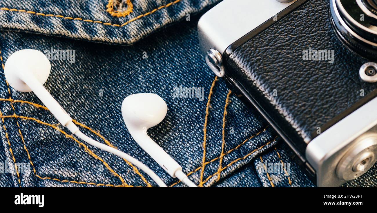 L'appareil photo et le casque avec fil blanc reposent sur l'arrière-plan du denim. Arrière-plan tendance des vêtements taille basse. Style rétro. Journée des photographes. Vue de dessus Banque D'Images