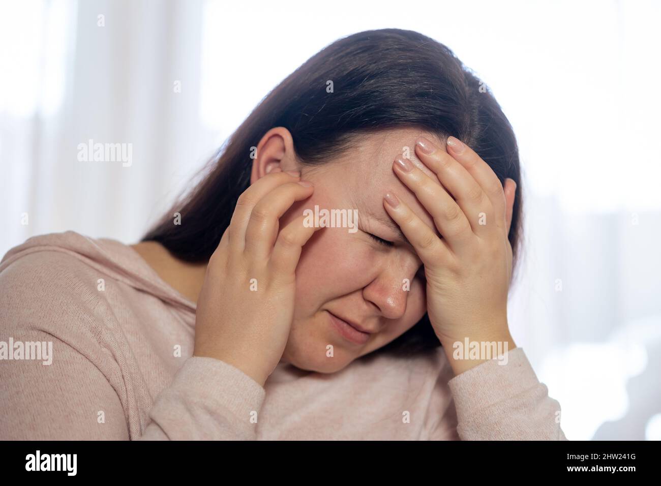 Jolie jeune femme souffrant d'acouphènes forts, malade femme ayant une douleur d'oreille touchant sa tête douloureuse, concept de santé Banque D'Images