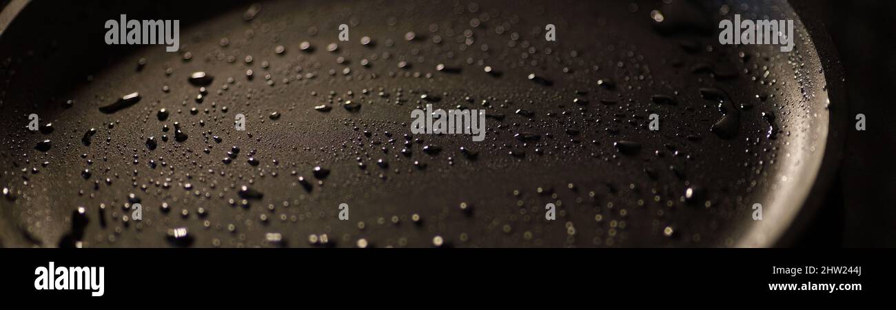 Fait partie d'une casserole vide en fonte de couleur noire avec des gouttes d'huile végétale. Gros plan. Arrière-plan sombre. Commencez la cuisson. Bannière Banque D'Images