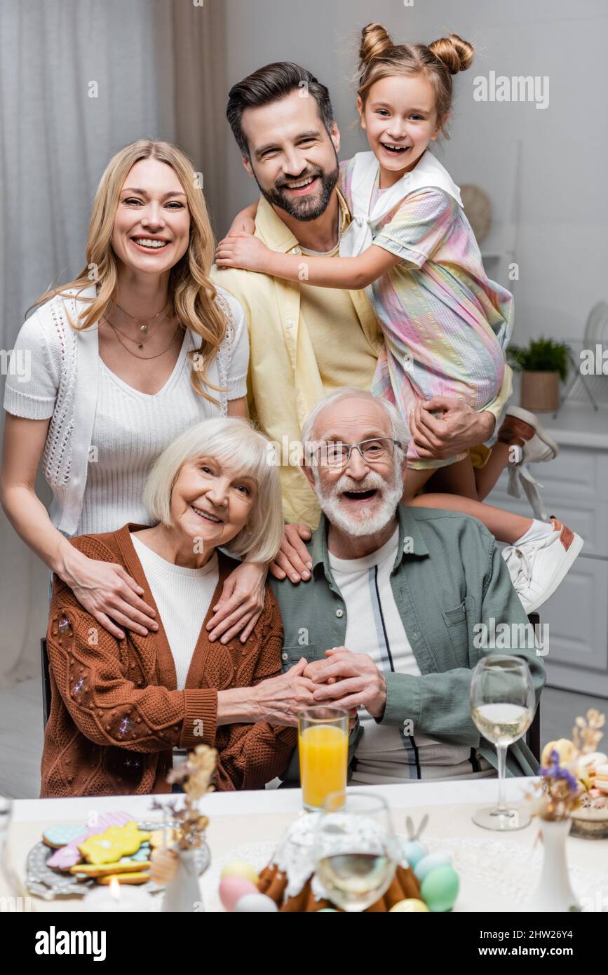 famille gaie regardant l'appareil photo près de la table avec le dîner de pâques, image de stock Banque D'Images