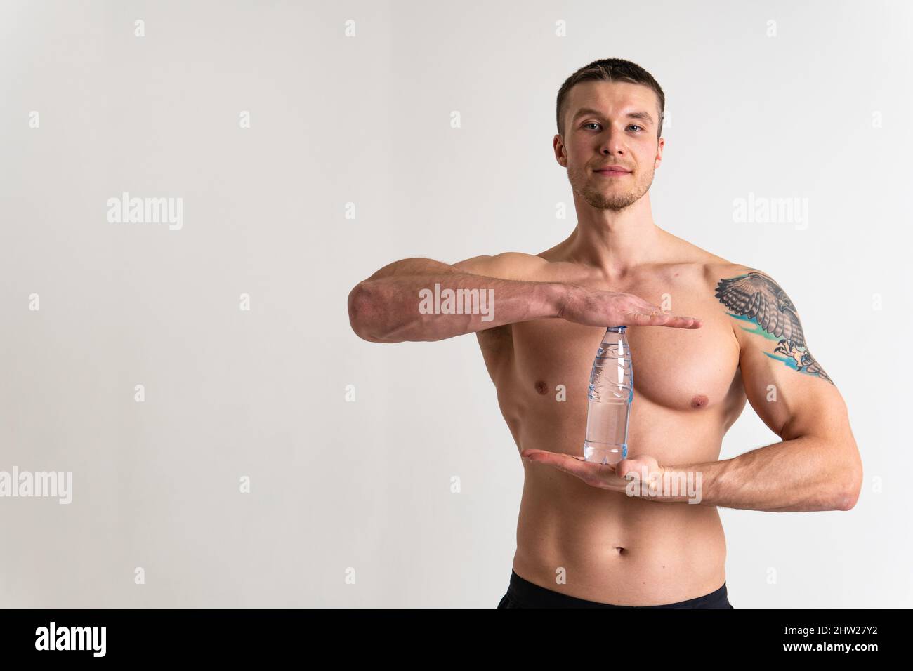 La forme physique à l'eau potable est pompée avec une serviette sur un fond blanc corps de forme physique isolé, l'exercice d'eau de la nutrition mâle tenue, protéine sportif Banque D'Images