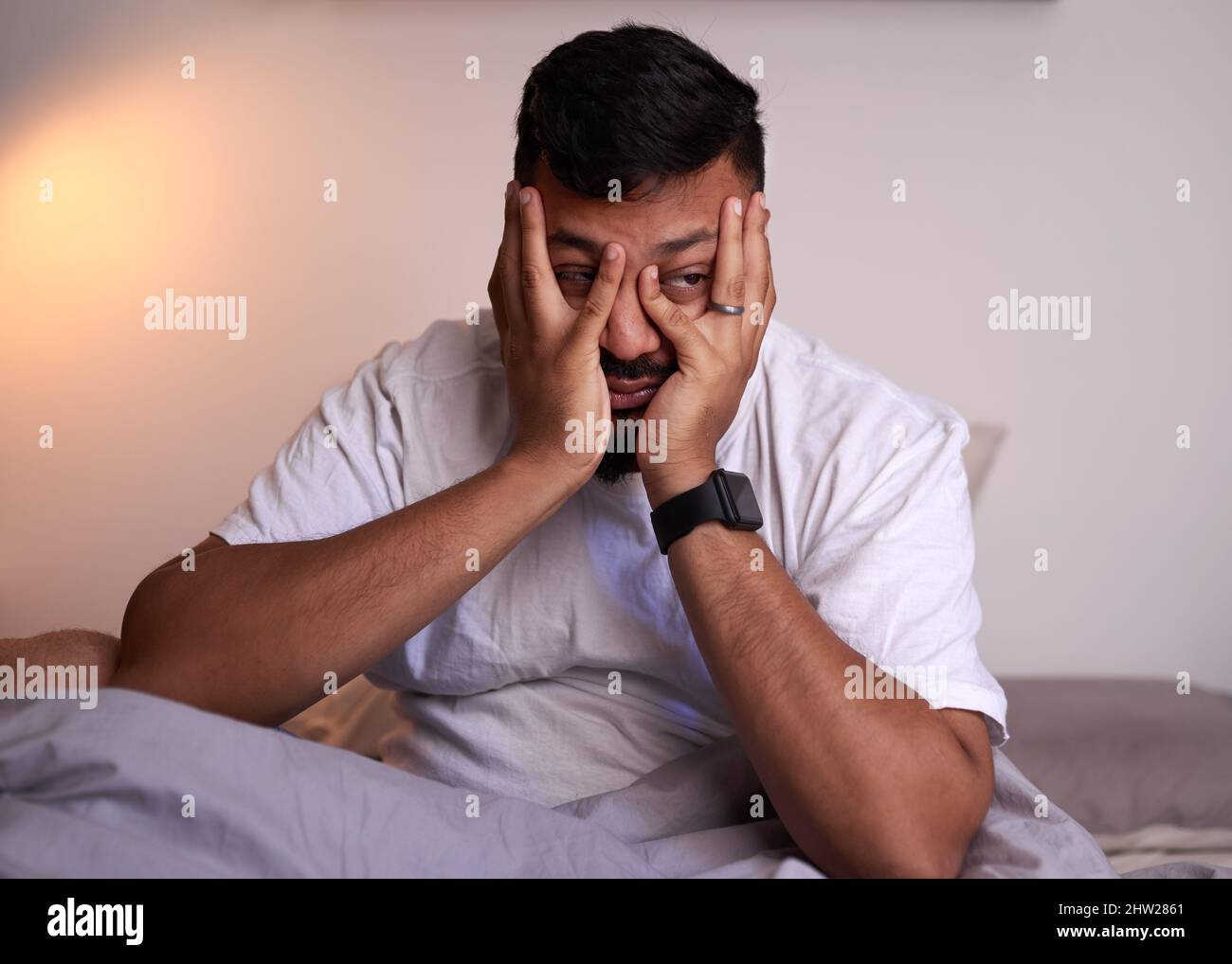 Un homme adulte couvre son visage luttant pour se réveiller tôt le matin Banque D'Images