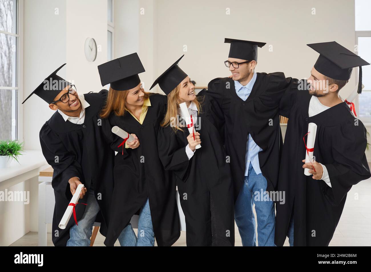 Groupe multiracial de diplômés universitaires heureux qui se embrasent et s'amusent en classe Banque D'Images