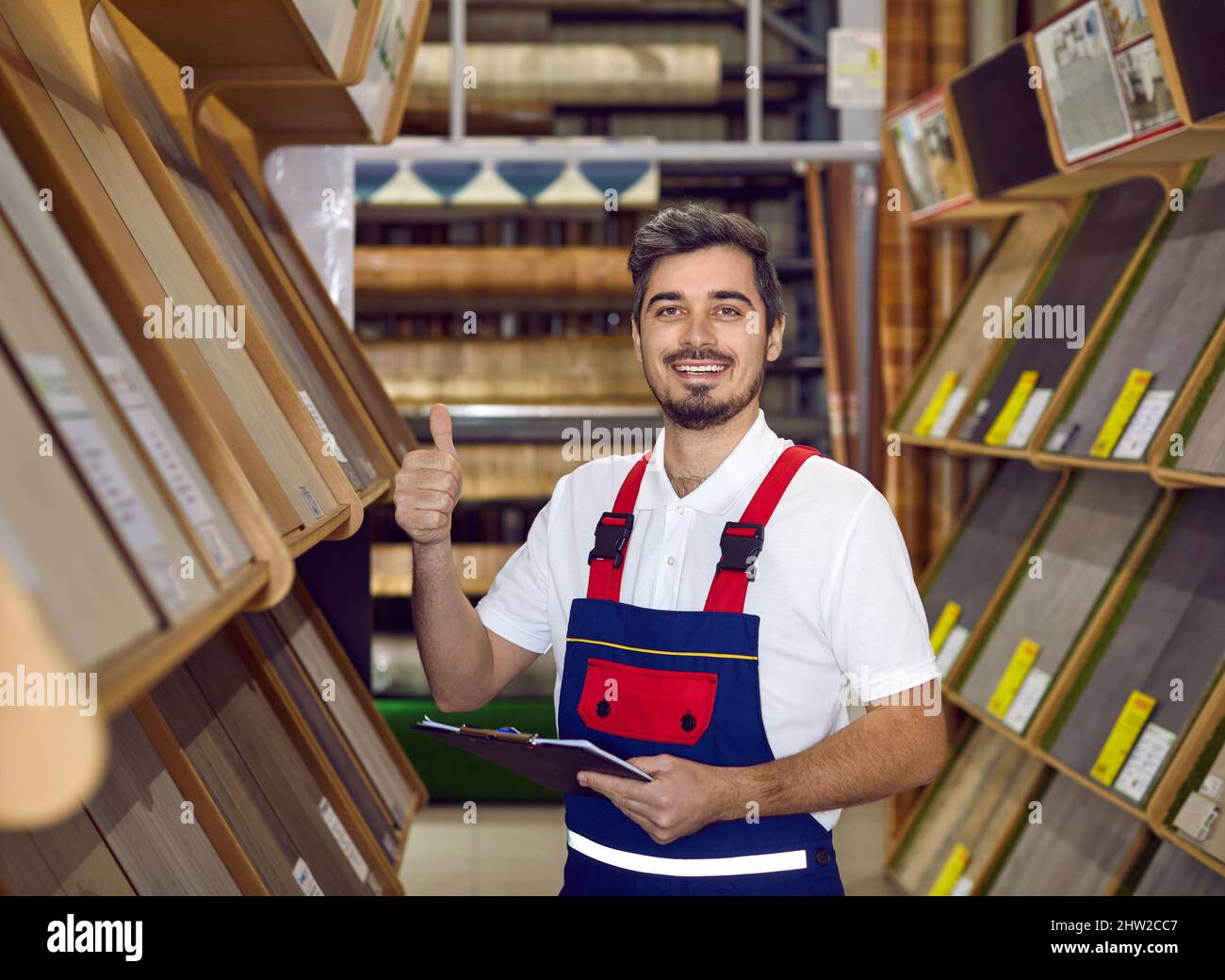 Heureux vendeur de plancher stratifié promettant la meilleure qualité, donnant les pouces et sourire Banque D'Images