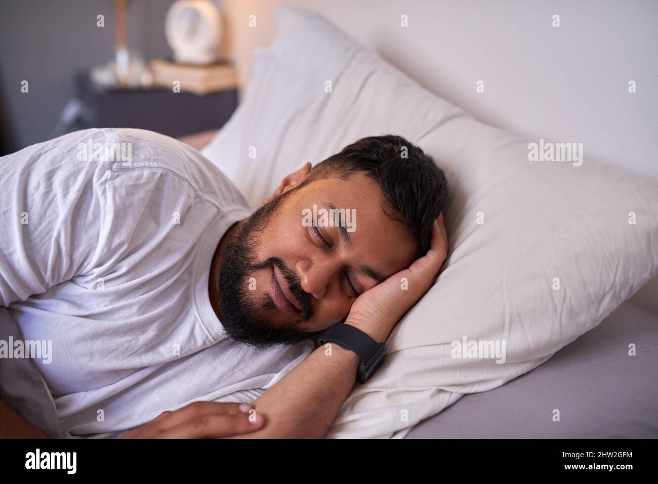 Un homme adulte dort paisiblement avec un sourire au lit le matin Banque D'Images