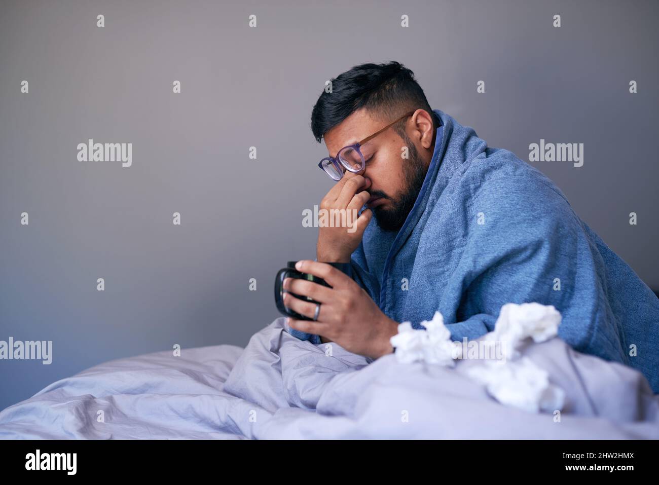 Un malade frotte ses sinus en s'asseyant au lit avec une boisson chaude. Copier l'espace Banque D'Images