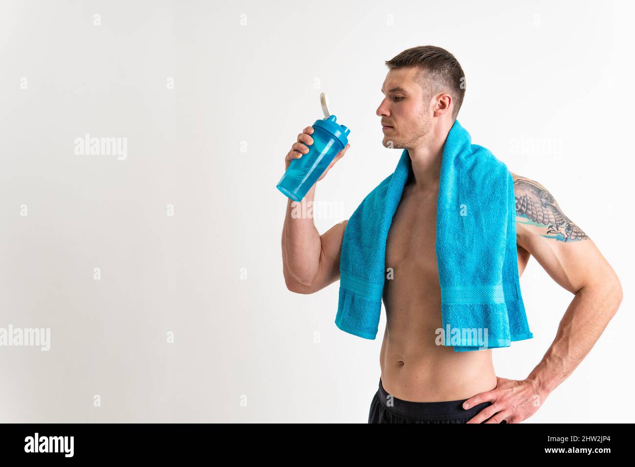 La forme physique à l'eau potable est pompée avec une serviette sur un fond blanc ajustement musculaire isolé style de vie, l'exercice à l'eau adulte athlétique. Soif de force Banque D'Images