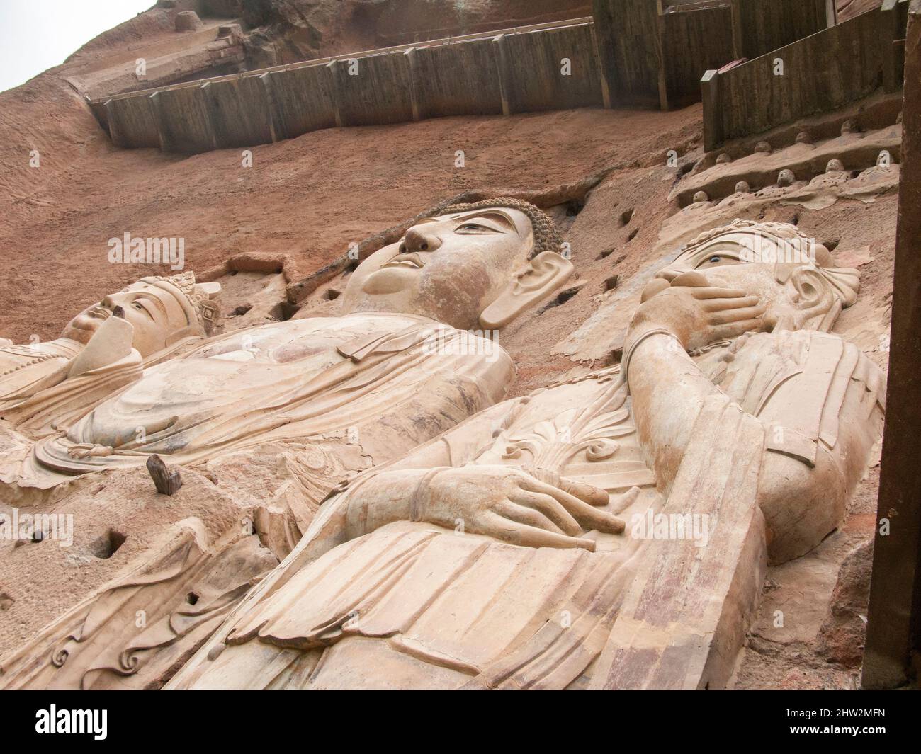 Représentations de Bouddha figures représentations et images bouddhistes (qui semble être restauré très récemment à l'aide de nouveaux matériaux) sur la face rocheuse des grottes de Maijishan, autrefois romanisée comme Maichishan, Qui sont une série de 194 grottes coupées sur le flanc de la colline de Majishan à Tianshui, province de Gansu, Chine. Des escaliers et des passerelles sont fixés à la face de roche pure pour permettre aux visiteurs d'entrer en contact étroit avec les figures d'argile et les anciennes sculptures en pierre sur le site. (67/125) Banque D'Images