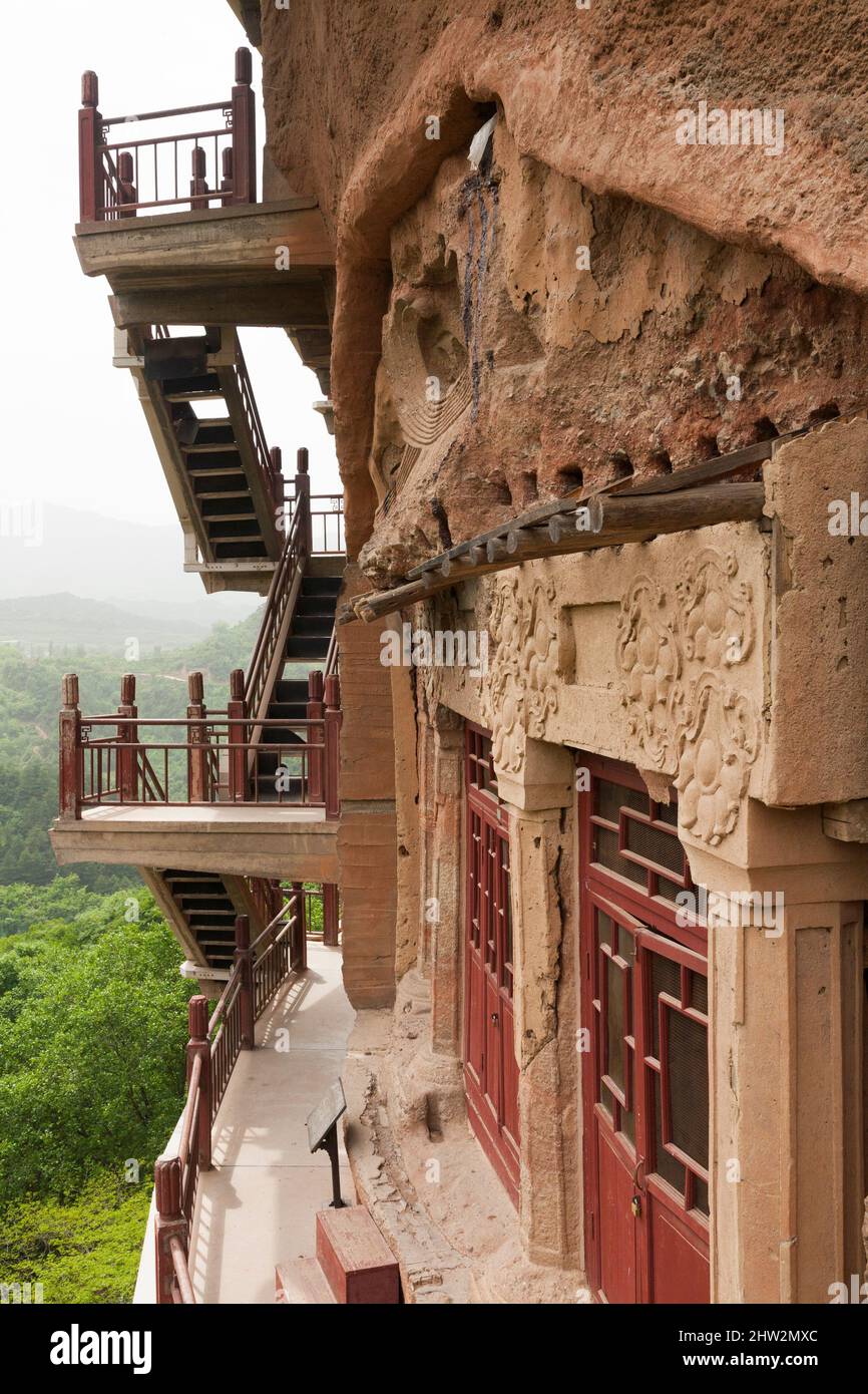 Les marches et les passerelles attachées à la roche permettent aux visiteurs de voir les anciennes statues en argile de Bouddha et de la statue de divinités bouddhistes attachées et sculptées dans la surface de pierre de la face de roche.les grottes de Maijishan, autrefois romanisées comme Maichishan, Sont une série de 194 grottes coupées sur le flanc de la colline de Majishan à Tianshui, province de Gansu, Chine. (67/125) Banque D'Images