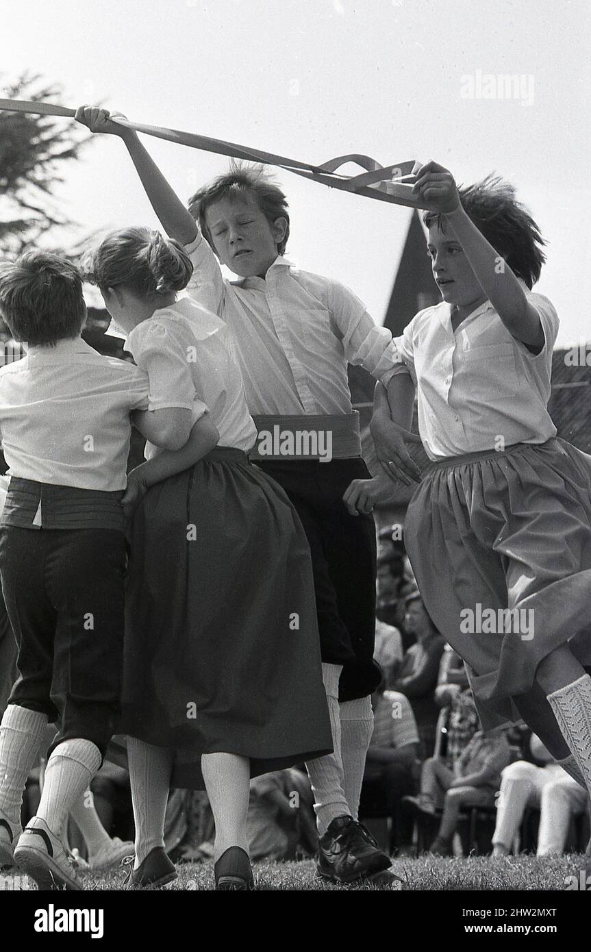 1987, les enfants qui se tiennent près d'un ruban pendant qu'ils dansent autour de la lypole, Popleton, Angleterre, Royaume-Uni. Danse folklorique cérémonielle autour d'un grand mât décoré de fleurs et de rubans, la danse de la lypole est une tradition ancienne datant des siècles aux danses autour des arbres pour célébrer l'arrivée du printemps. Au village vert de Popleton, York, les enfants de l'école primaire dansaient autour d'un typole chaque année depuis 1945. Banque D'Images