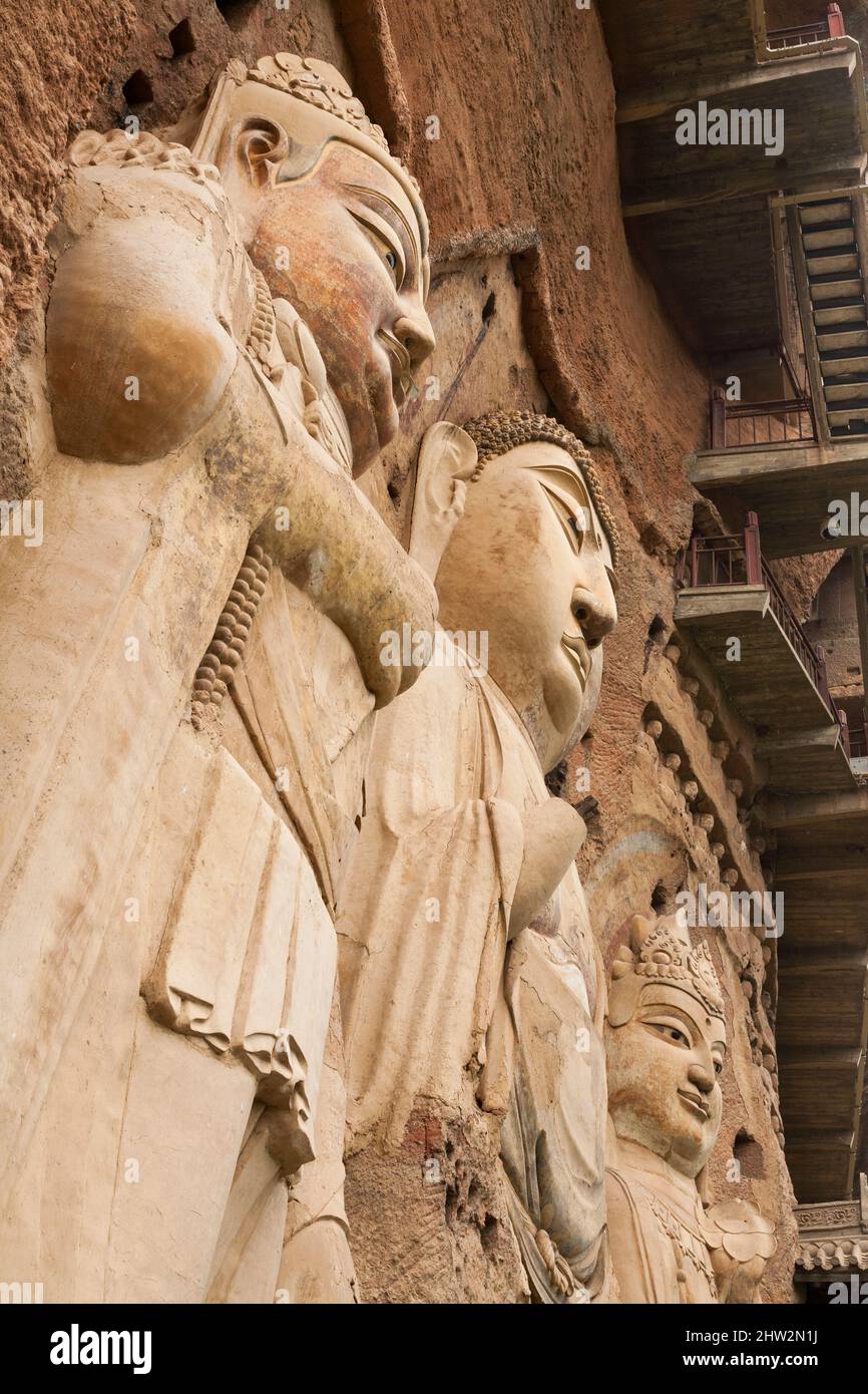 Représentations de Bouddha figures représentations et images bouddhistes (qui semble être restauré très récemment à l'aide de nouveaux matériaux) sur la face rocheuse des grottes de Maijishan, autrefois romanisée comme Maichishan, Qui sont une série de 194 grottes coupées sur le flanc de la colline de Majishan à Tianshui, province de Gansu, Chine. Des escaliers et des passerelles sont fixés à la face de roche pure pour permettre aux visiteurs d'entrer en contact étroit avec les figures d'argile et les anciennes sculptures en pierre sur le site. (67/125) Banque D'Images