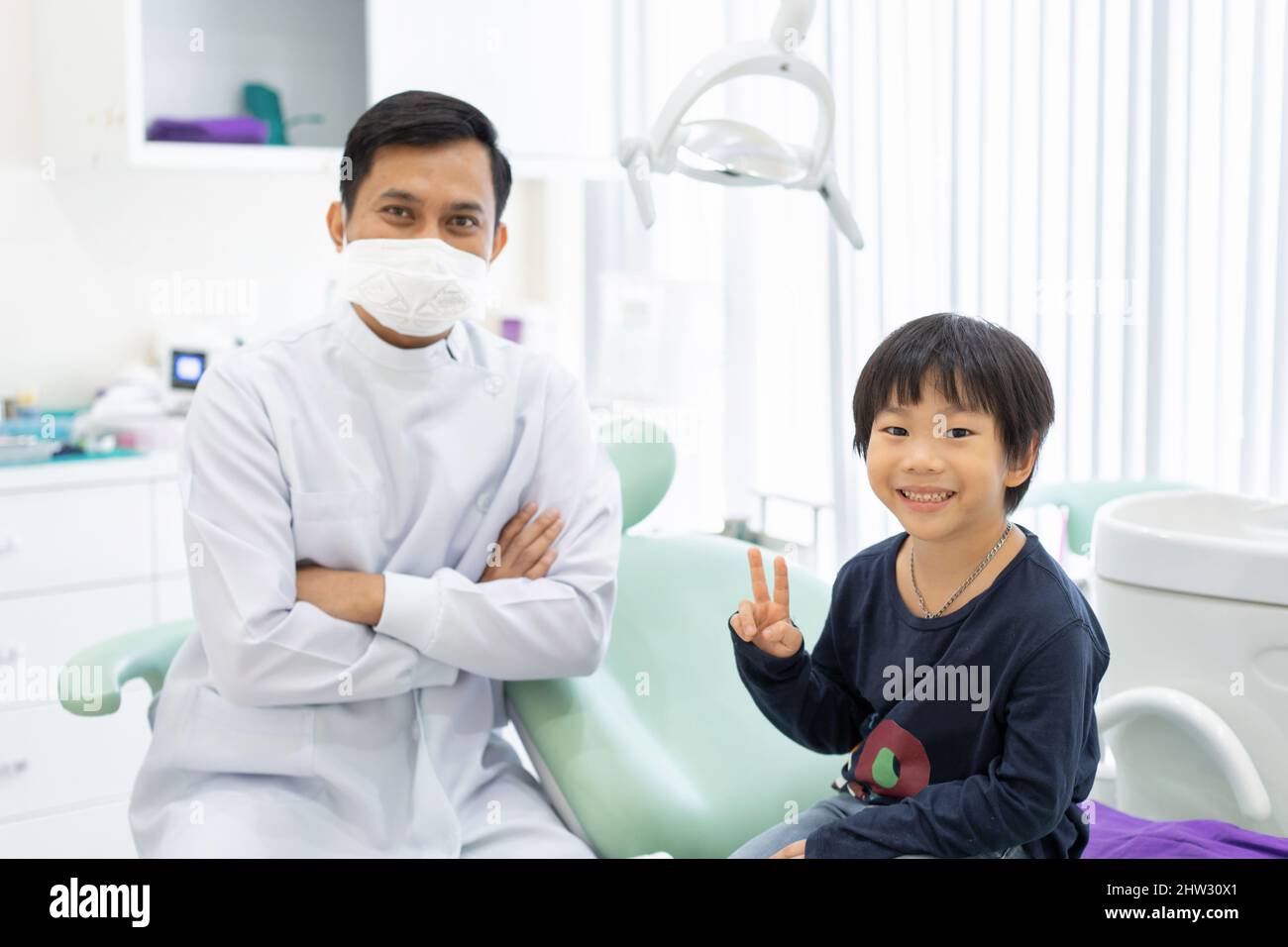 Le garçon asiatique se sent heureux de s'asseoir sur la chaise dentaire avec le dentiste en clinique dentaire Banque D'Images