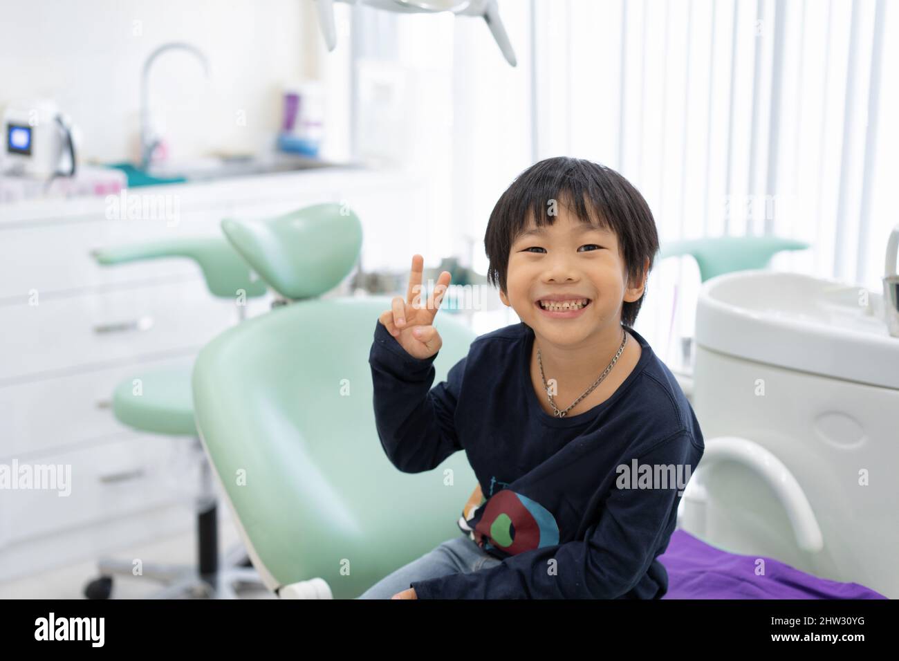Le garçon asiatique se sent heureux de s'asseoir sur la chaise dentaire dans la clinique dentaire Banque D'Images