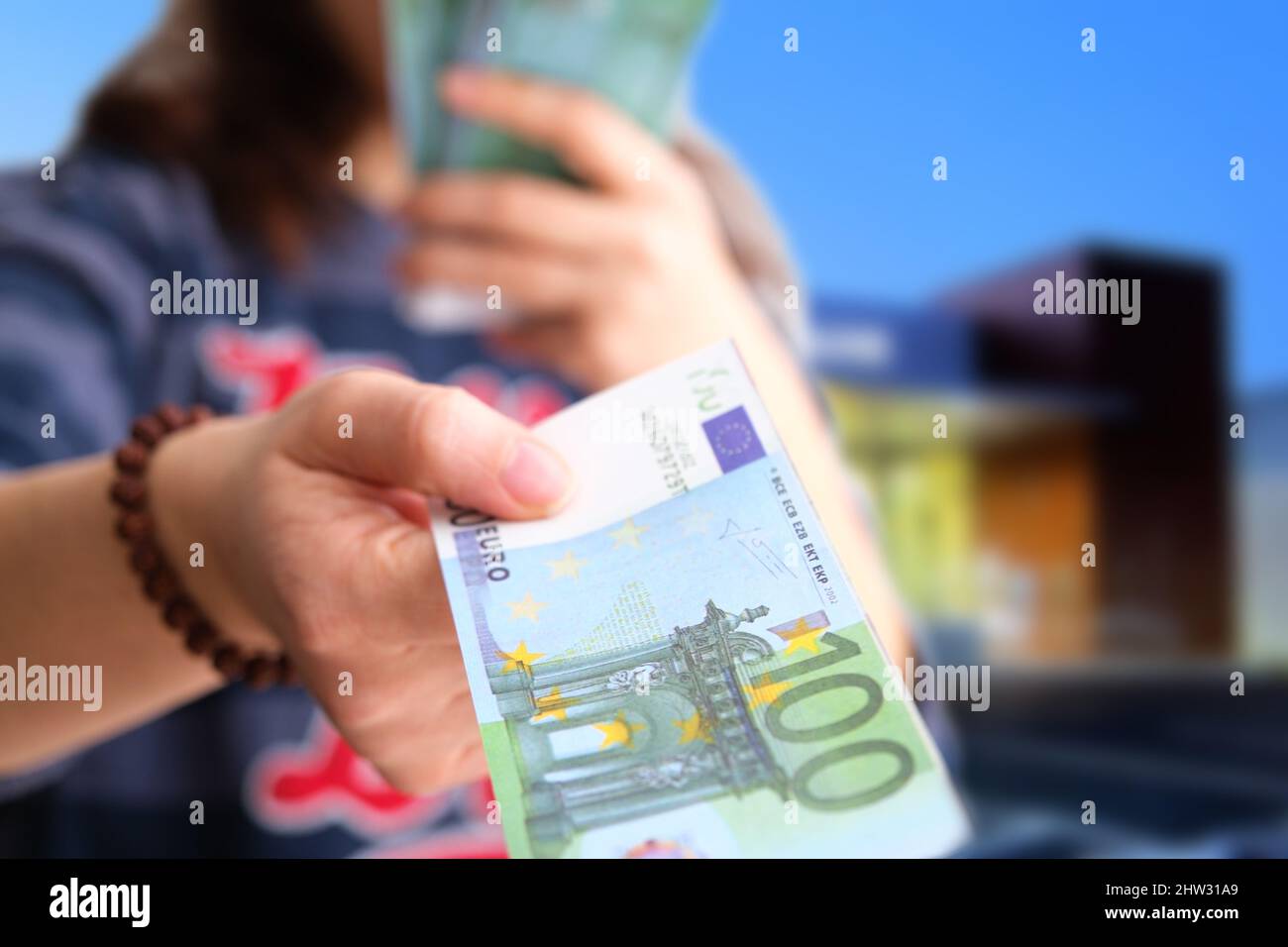 Main féminine ne donnant qu'un seul billet d'argent pour un paiement sur fond bancaire, gros plan de l'adulte du caucase distribuant la monnaie de l'Union européenne, l'euro. Banque D'Images