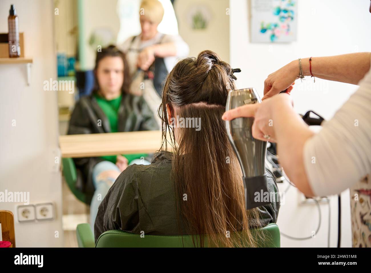 Coiffeur sèche et coiffe les cheveux avec un sèche-cheveux dans le salon de beauté Banque D'Images