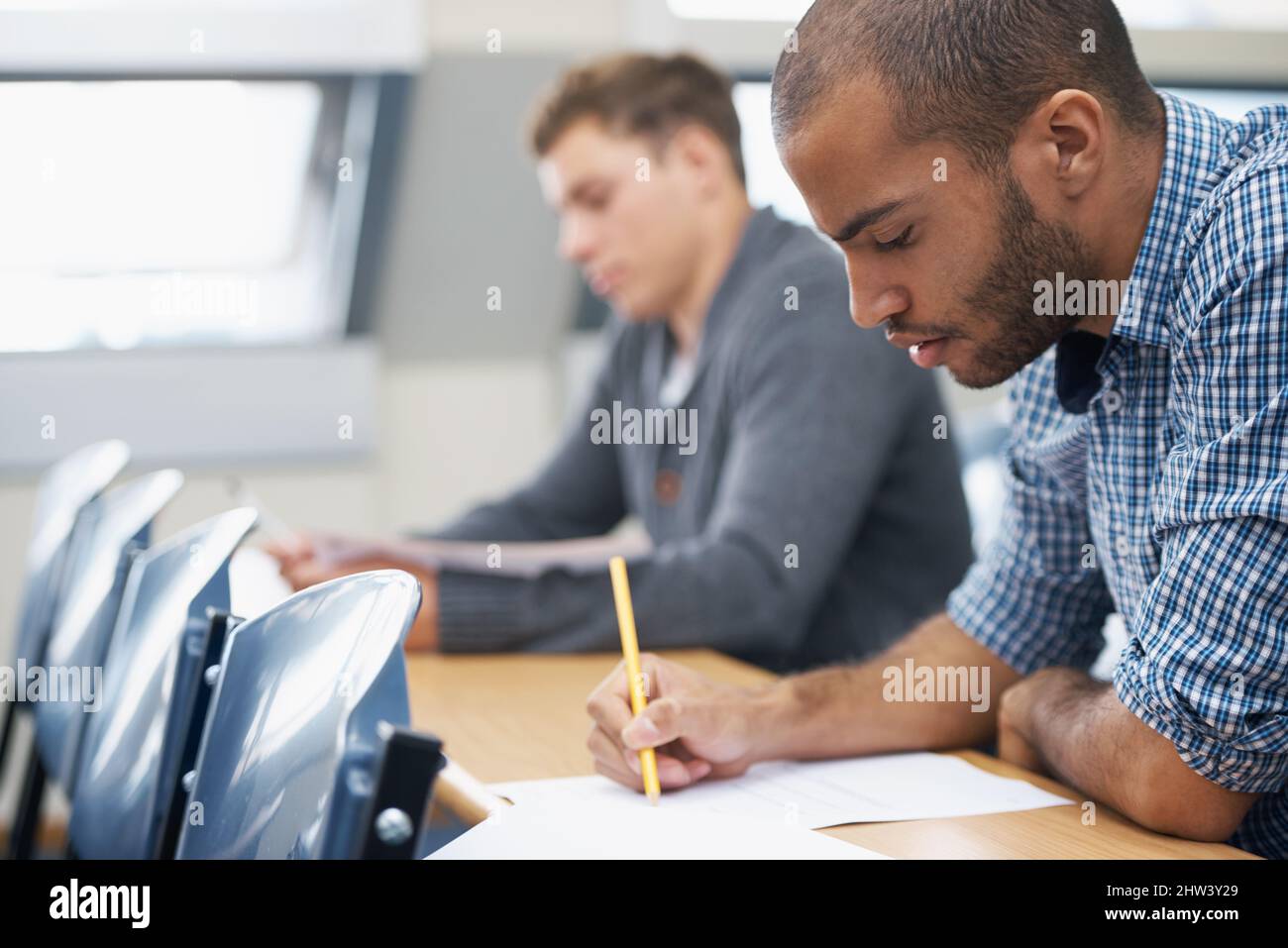 Tout est à l'épreuve Deux étudiants de sexe masculin rédigeant un examen dans une salle de conférence. Banque D'Images