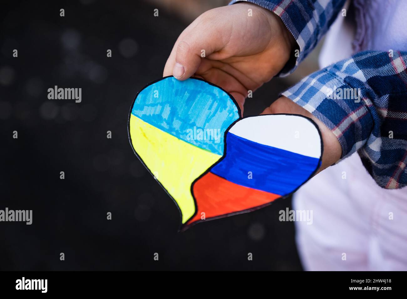 Les drapeaux ukrainiens et russes ensemble dans le coeur dans les mains des enfants. Concept de mettre fin à la guerre en Ukraine et de réconciliation Banque D'Images
