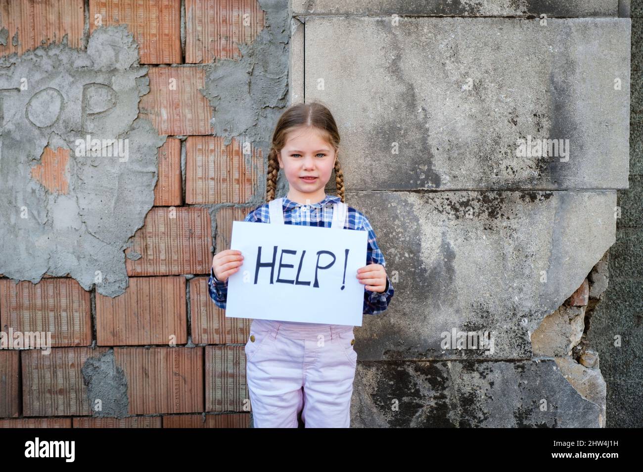Enfant fille tenant une affiche avec l'AIDE écrite pour soutenir la paix. Concept de "pas de guerre" en Ukraine et dans le monde. Conflit russe en faveur du pois Banque D'Images