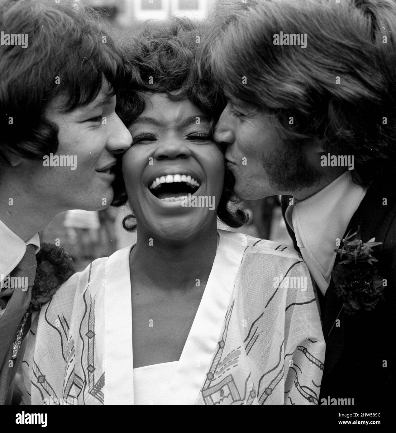 La chanteuse pop américaine P.P. Arnold reçoit un baiser de son nouveau mari, le gérant Jim Morrison (à gauche) et Barry Gibb du groupe pop Bee Gees le jour de son mariage, le 1968 octobre Banque D'Images