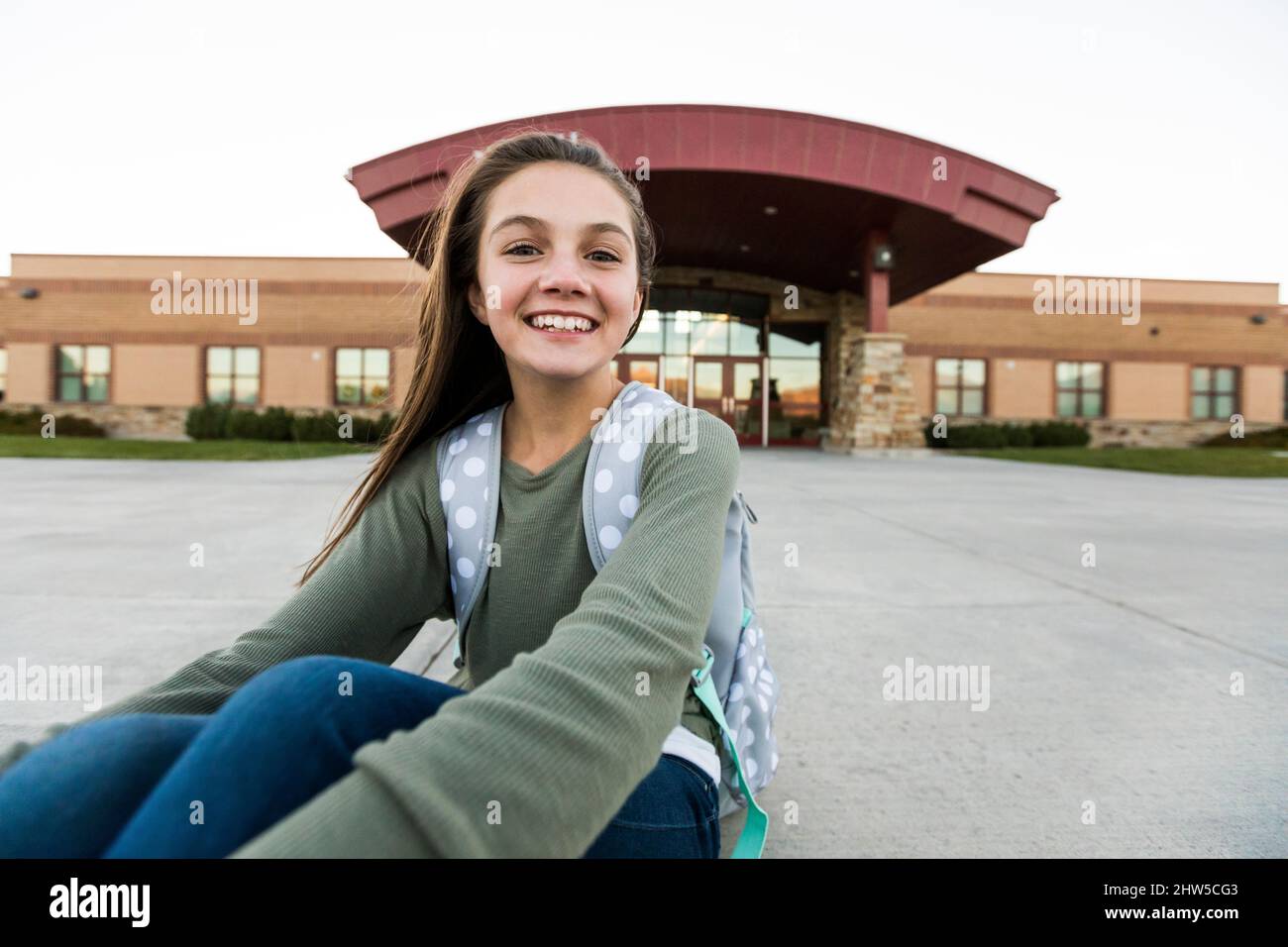 États-Unis, Utah, Lehi, Portrait de fille souriante (12-13) assis devant le bâtiment de l'école Banque D'Images