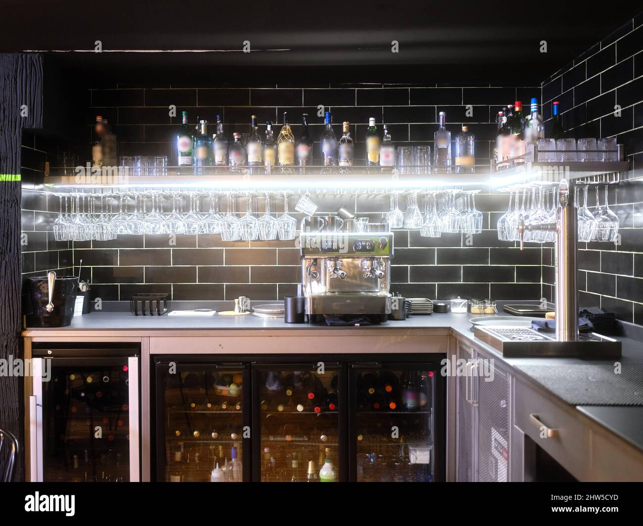 Restaurant avec des verres suspendus à un porte-bouteilles et des bouteilles de vin dans le réfrigérateur Banque D'Images