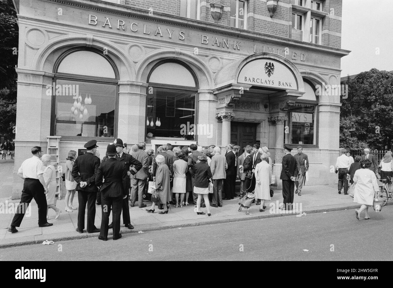 Le premier guichet automatique de Worlds, Cash machine, est dévoilé à la Barclays Bank, à Enfield, Middlesex, juste au nord de Londres. 27th juin 1967. La photo montre la foule de clients et de spectateurs locaux, voyant le premier guichet automatique au monde travailler pour la première fois. Barclays ATM, 27th juin 1967. Sir Thomas Bland, vice-président de Barclays Bank, dévoile un robot de caisse qui distribue de l'argent à tout moment du jour ou de la nuit. Conçue et développée conjointement avec de la rue instruments et le service des services de gestion des banques, la machine BarclayCash est installée dans la succursale d'Enfield. L'acteur Reg Varney a pris le temps de quitter Filmi Banque D'Images