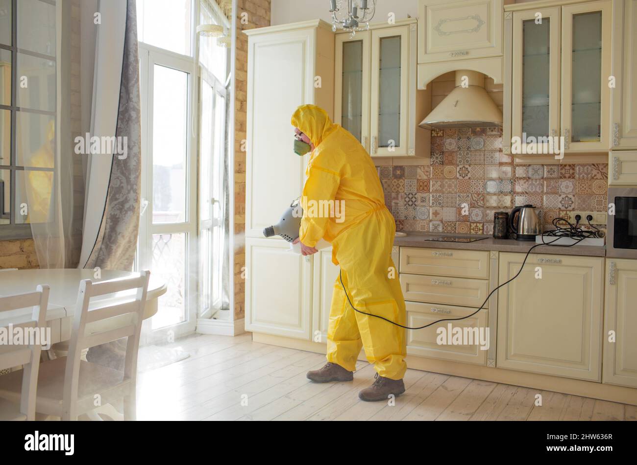 Un homme, spécialiste de la lutte contre les insectes, dans une combinaison  de protection jaune vaporise les murs de l'appartement, protège contre les  virus Photo Stock - Alamy