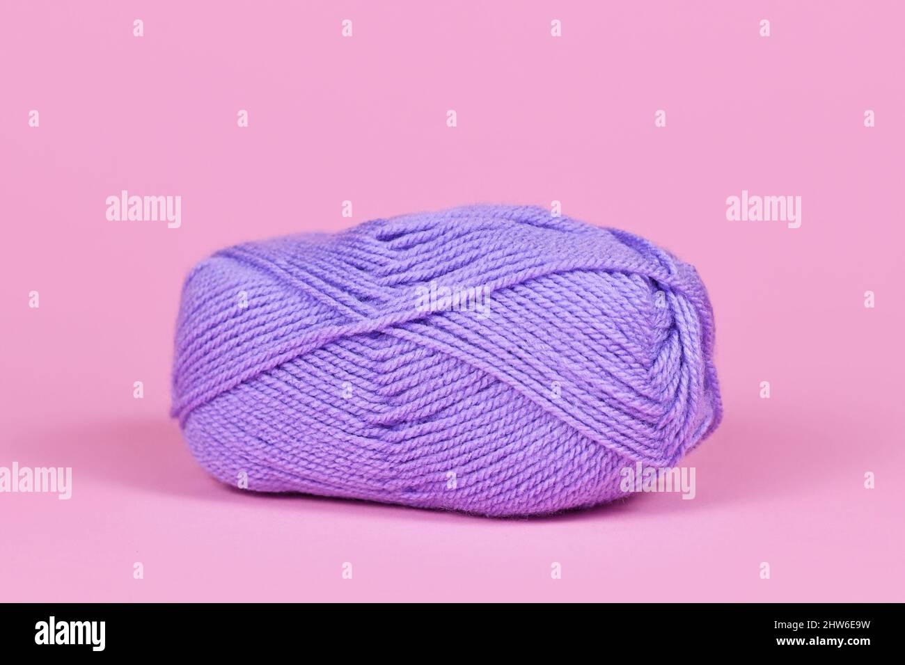 Une boule de laine violette sur fond rose Banque D'Images