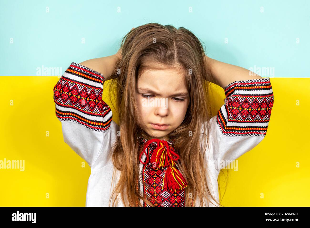 Une fille pleure, tenant une AFFICHE D'ARRÊT sur le fond du drapeau ukrainien. Arrêter la guerre en Ukraine. Le concept de paix en Ukraine. Banque D'Images