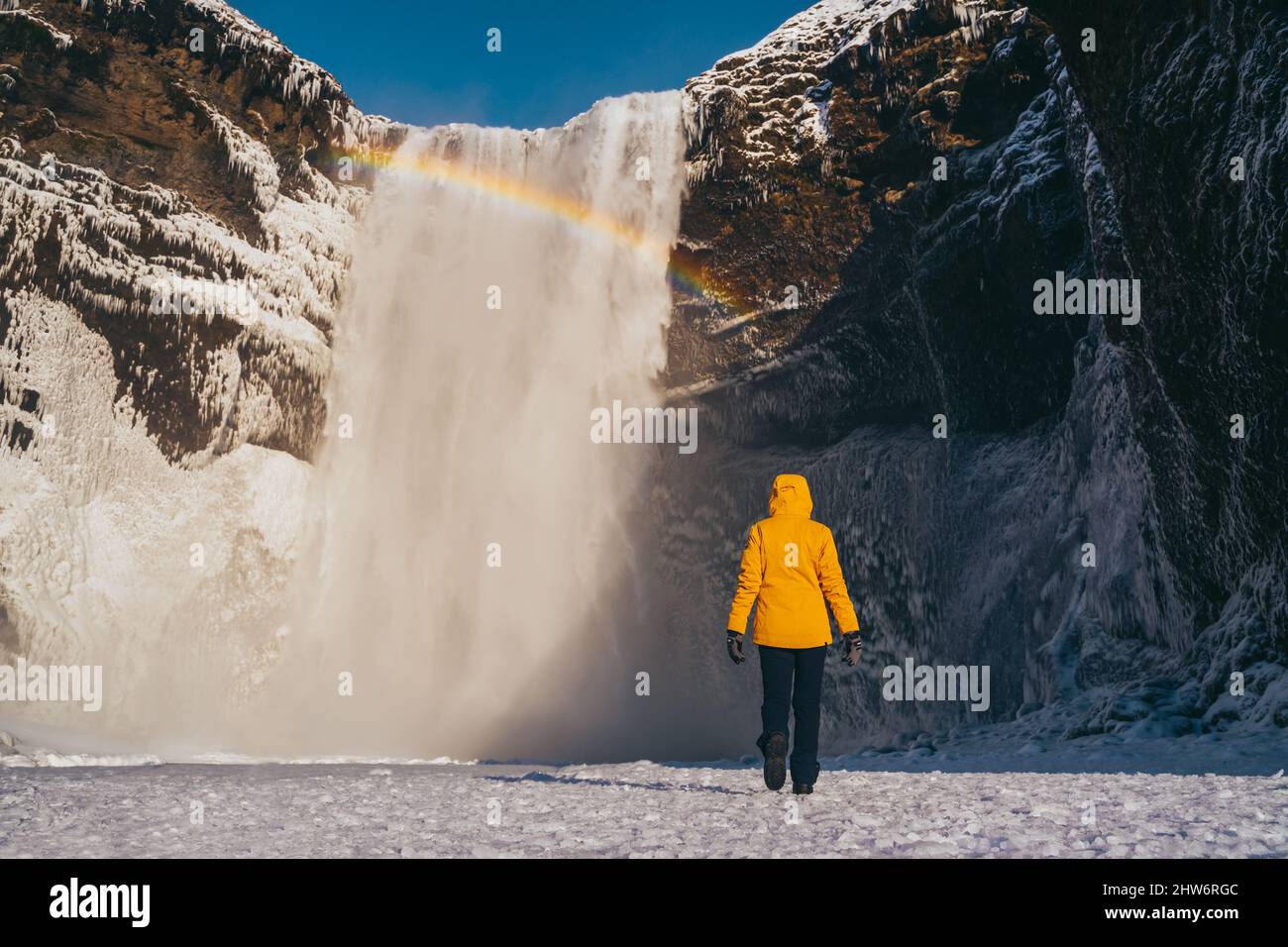 Femme espagnole avec un manteau jaune à la cascade de skogafoss Banque D'Images