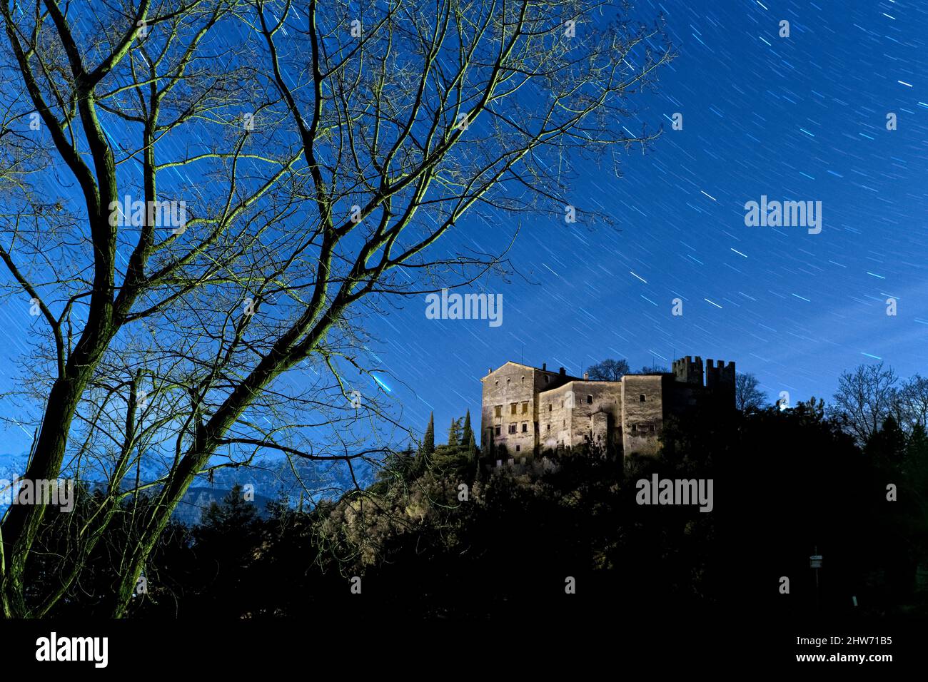Des arbres squelettiques encadrent le château de Madruzzo lors d'une nuit effrayante. Madruzzo, Trento province, Trentin-Haut-Adige, Italie, Europe. Banque D'Images