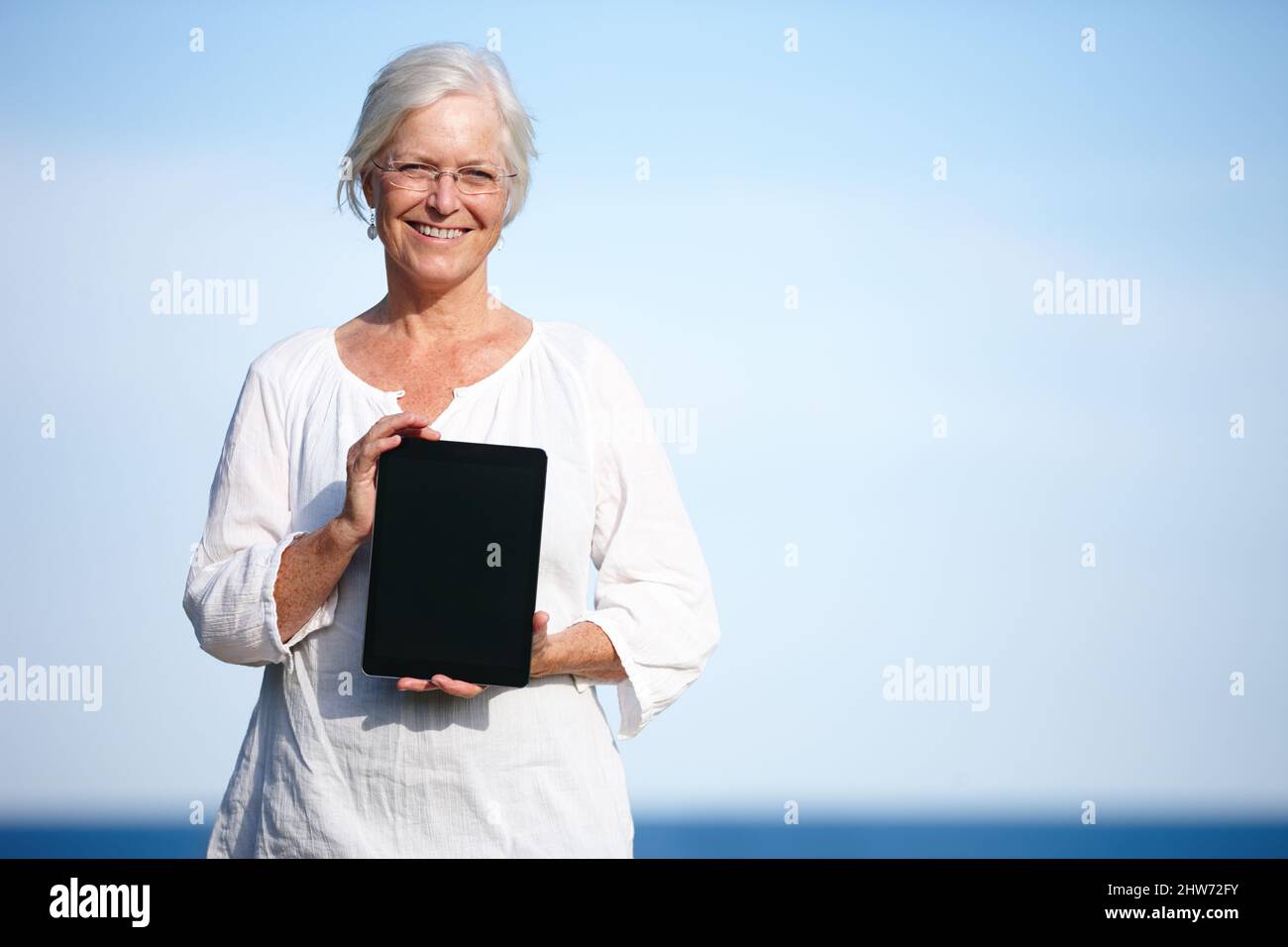 Shes a trouvé de grands exercices de relaxation en ligne. Portrait d'une femme mûre tenant une tablette numérique debout à l'extérieur. Banque D'Images