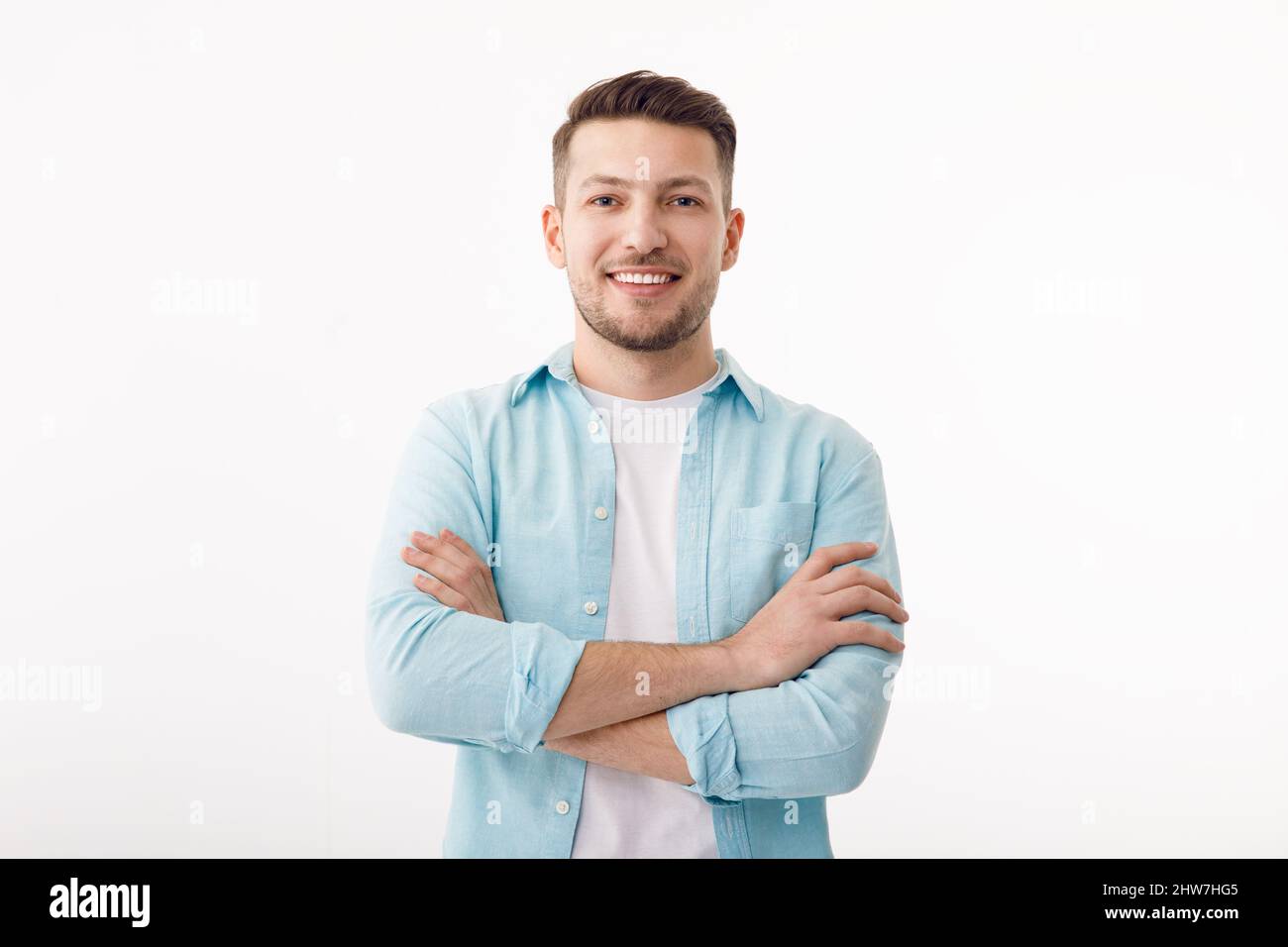 Portrait d'un jeune homme joyeux dans un T-shirt blanc sur fond blanc. Le gars est debout regardant la caméra et souriant. Banque D'Images