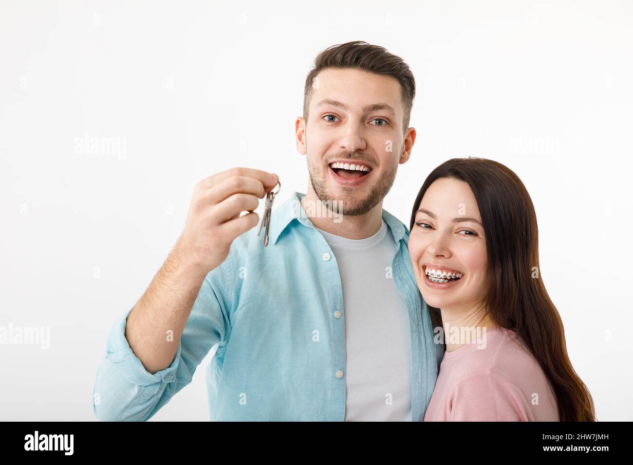 Un jeune couple gai est embrassant dans la cuisine, tenant les clés d'une nouvelle maison dans leurs mains. Heureux newlyweds déplacé dans un nouvel appartement, a eu un Banque D'Images