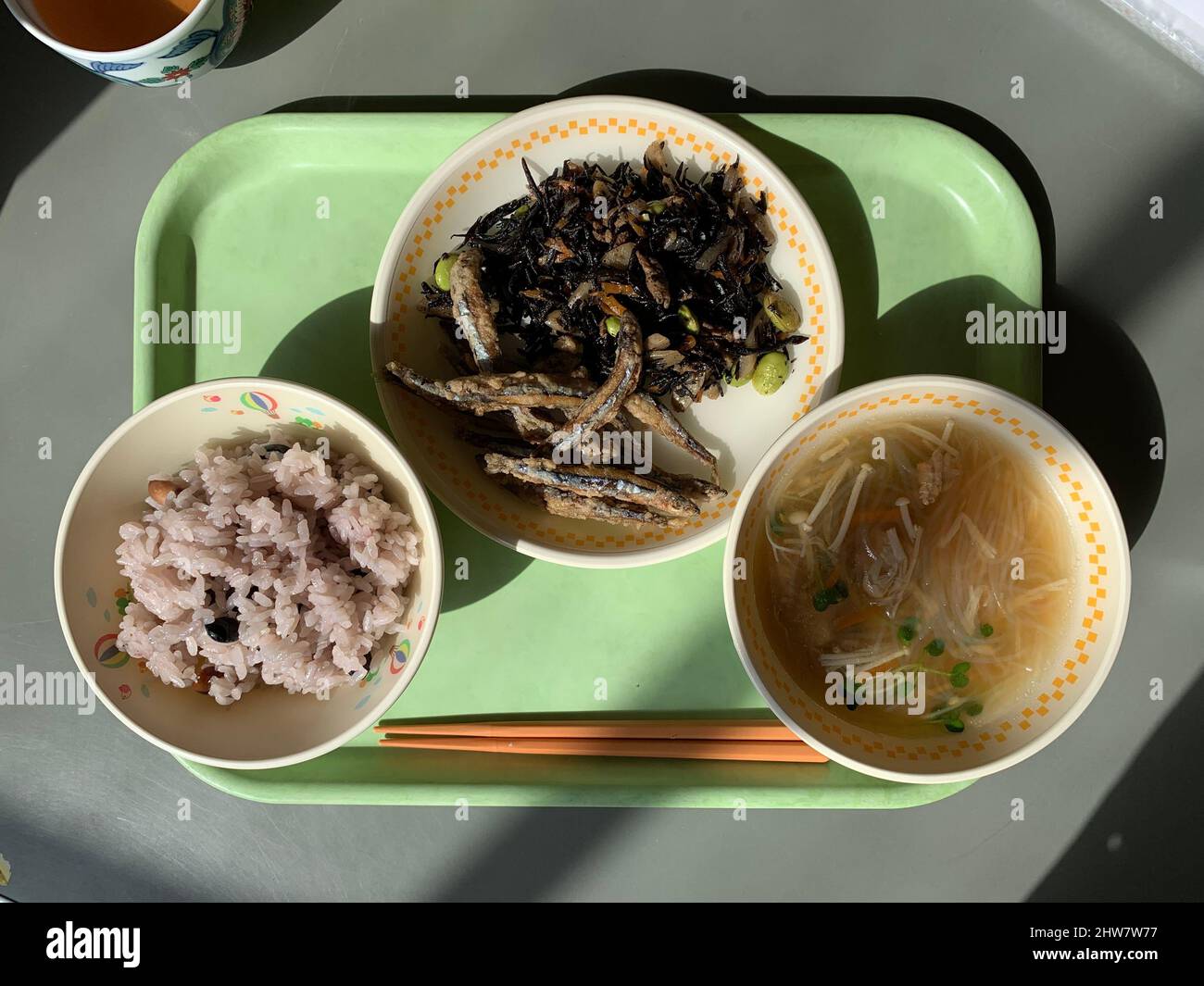 Déjeuner à l'école japonaise sur un plateau en plastique vert riz, soupe et anchois frits Banque D'Images