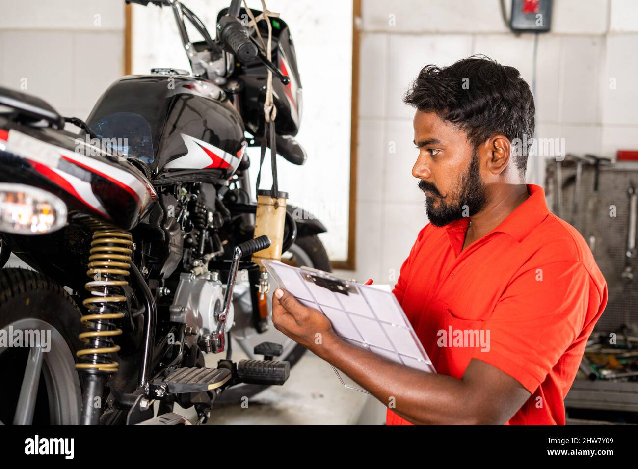 mécanicien occupé à noter les pièces de réparation de vélo pendant la réparation d'entretien au grage pour le client - concept d'occupation professionnelle, de l'homme de réparation et de compétence Banque D'Images