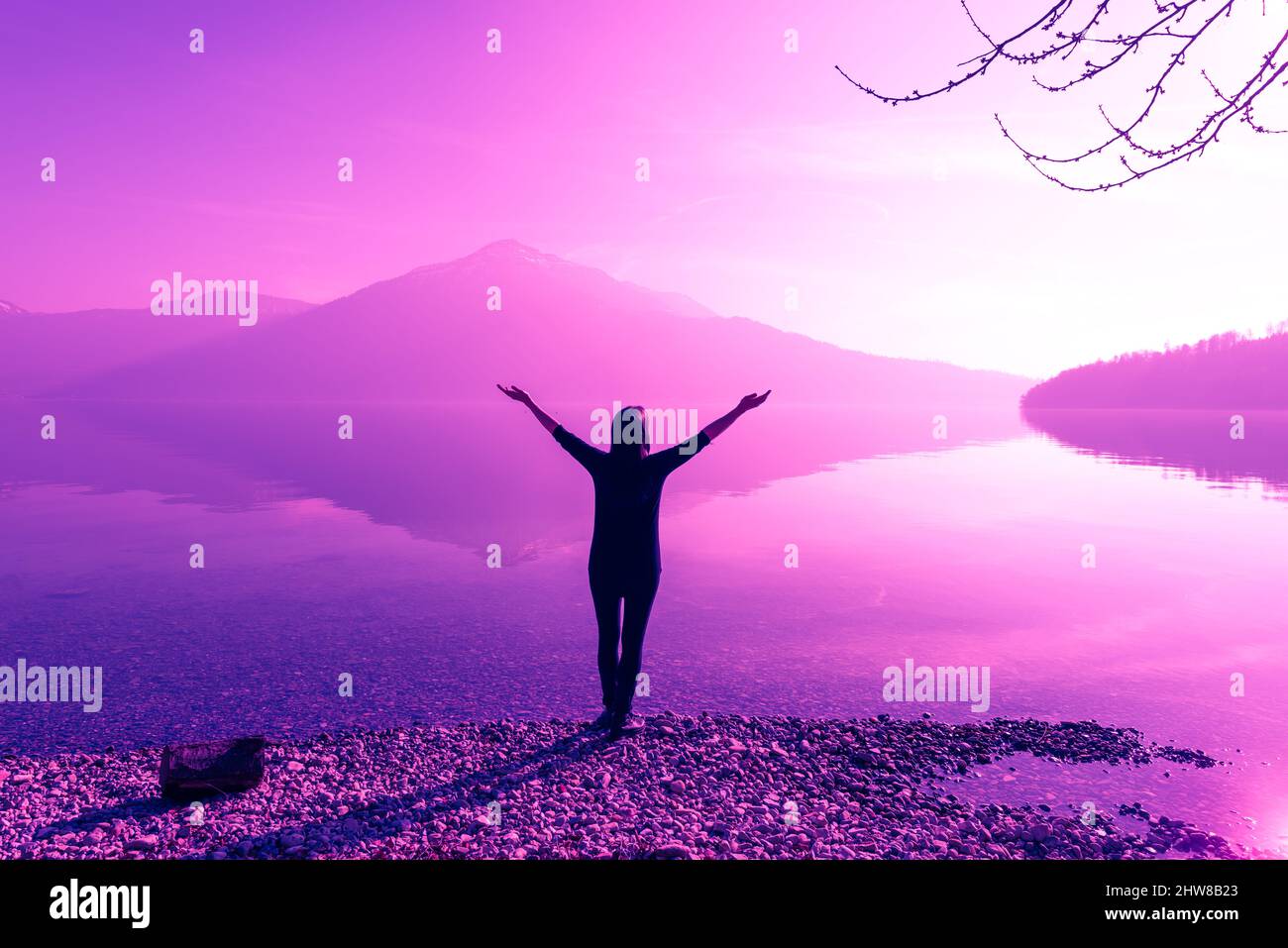 Figure féminine à bras ouverts larges. La nature fantastique des sommets de montagne reflétés dans l'eau du lac. La lumière vive du soleil. Banque D'Images