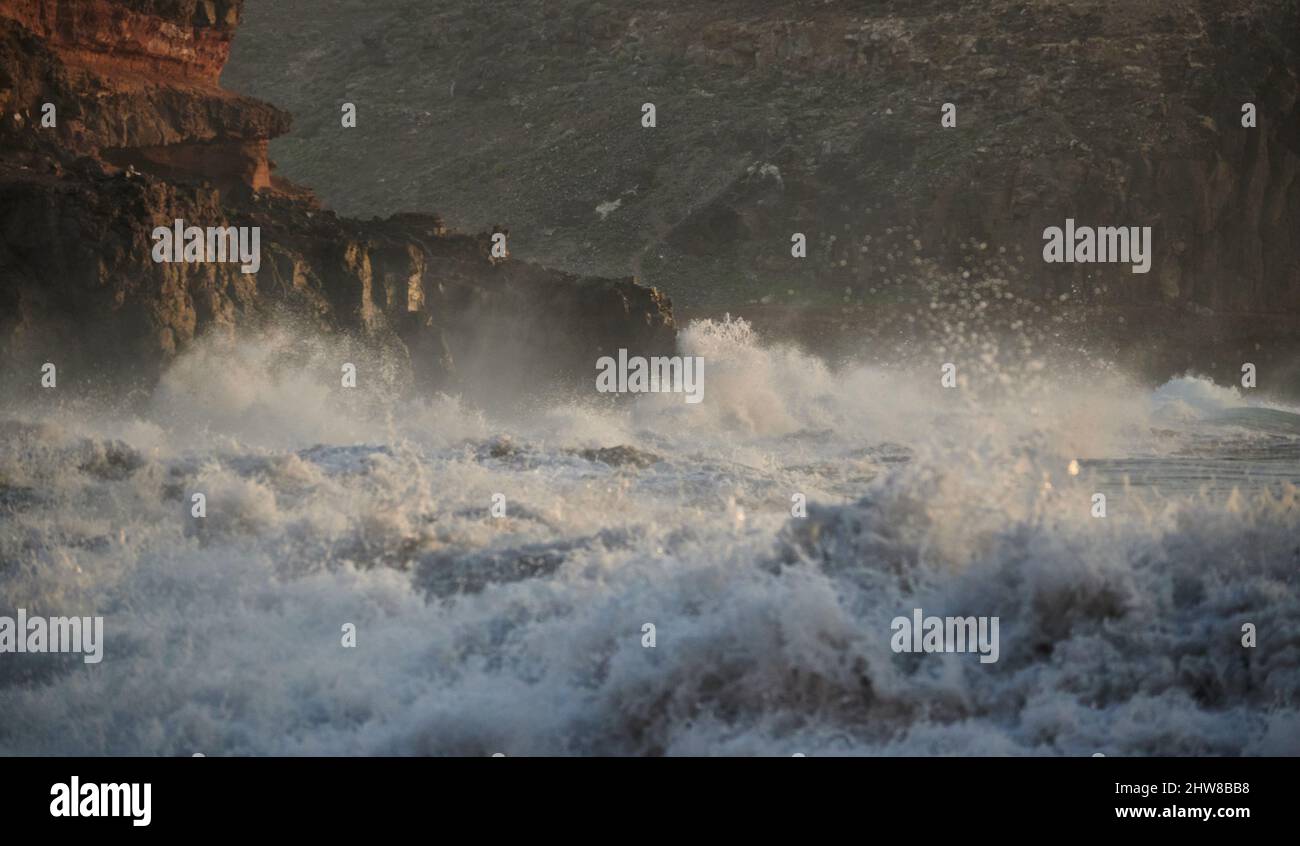 Vue sur les vagues de la mer qui font rage et qui battaient une falaise rocheuse sur la côte en arrière-plan de la région montagneuse Banque D'Images