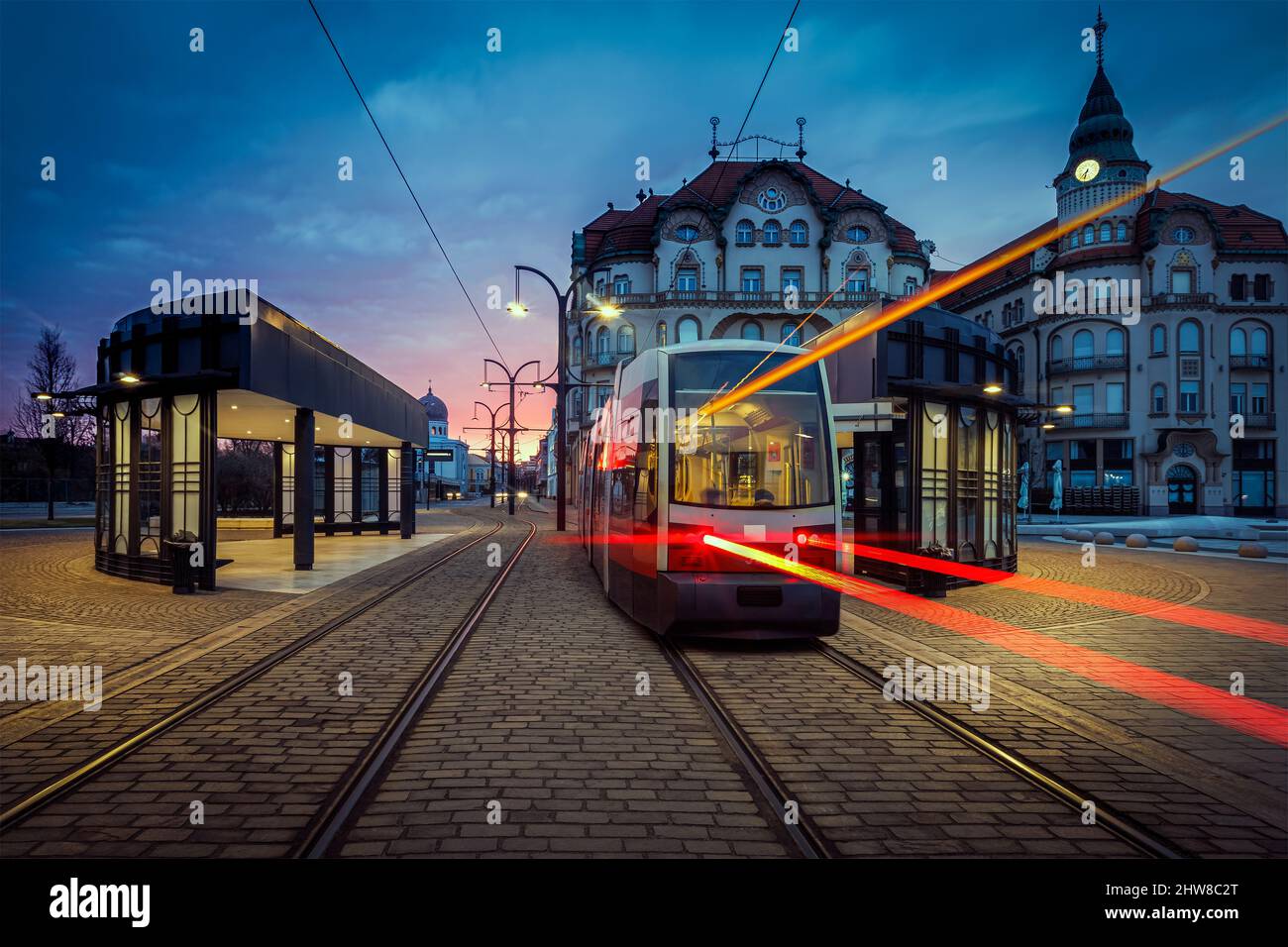 Lever de soleil spectaculaire sur Union Square d'Oradea avec le tramway arrivant à la gare. Photo prise le 19th février 2022 à Oradea, comté de Bihor, Transylvanie Banque D'Images