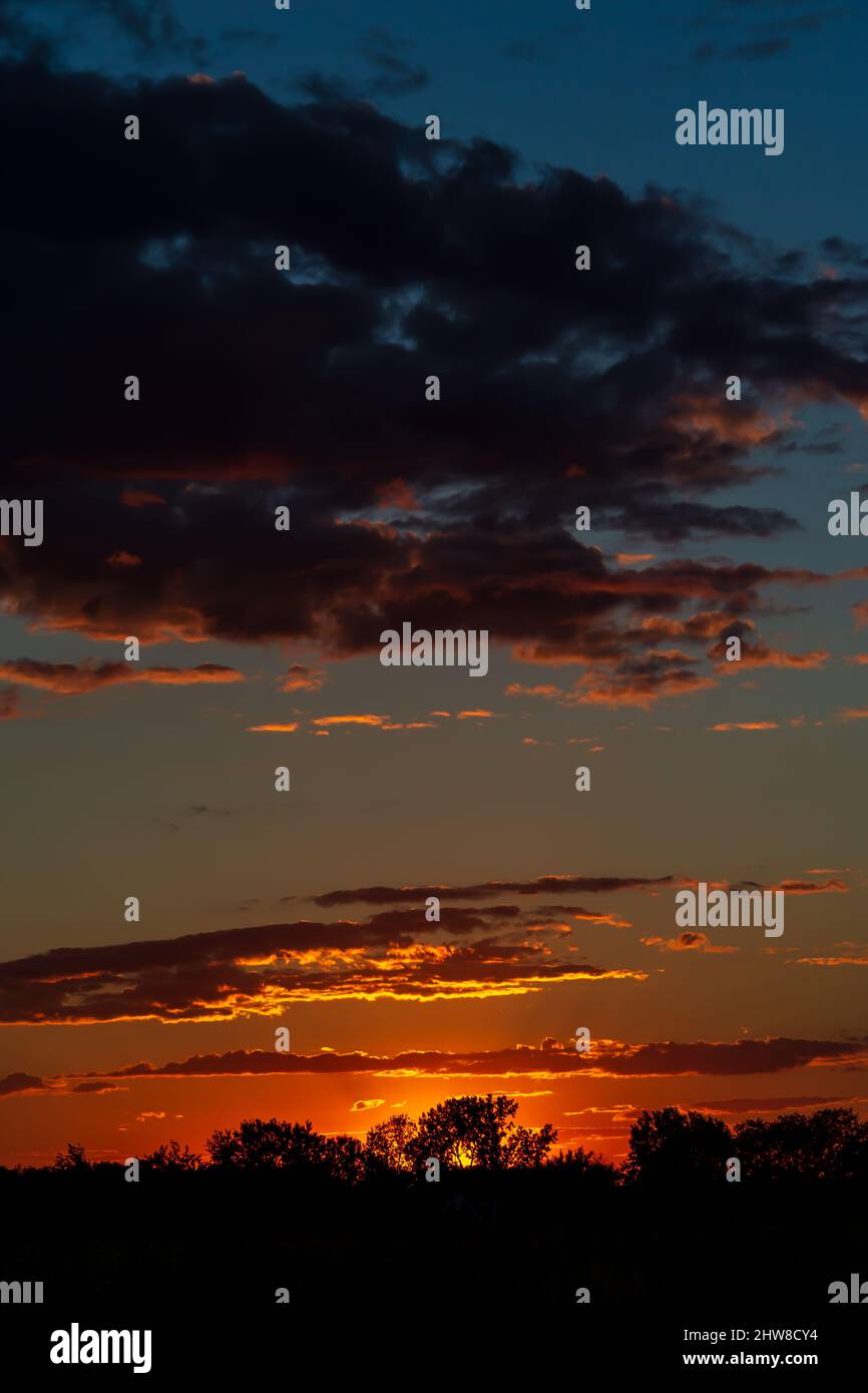 La lumière du soleil se reflète sur les nuages tandis que le soleil se couche au-dessous de l'horizon. Banque D'Images