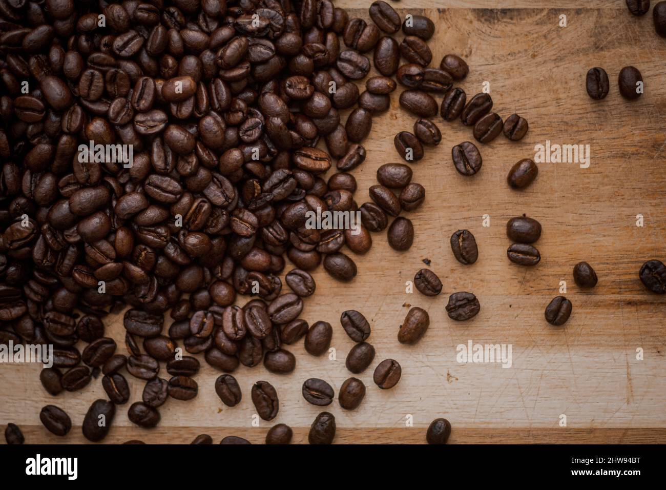 Un gros plan de haricots bruns de café torréfié farcis sur une table en bois Banque D'Images