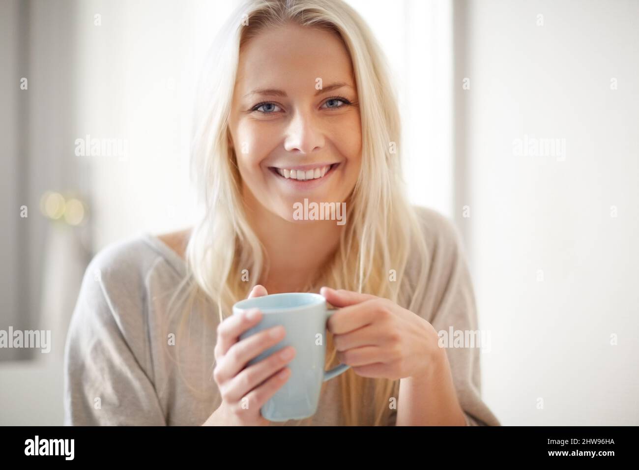 Un coup de pouce le matin. Une jolie jeune femme savourant une tasse de café le matin. Banque D'Images