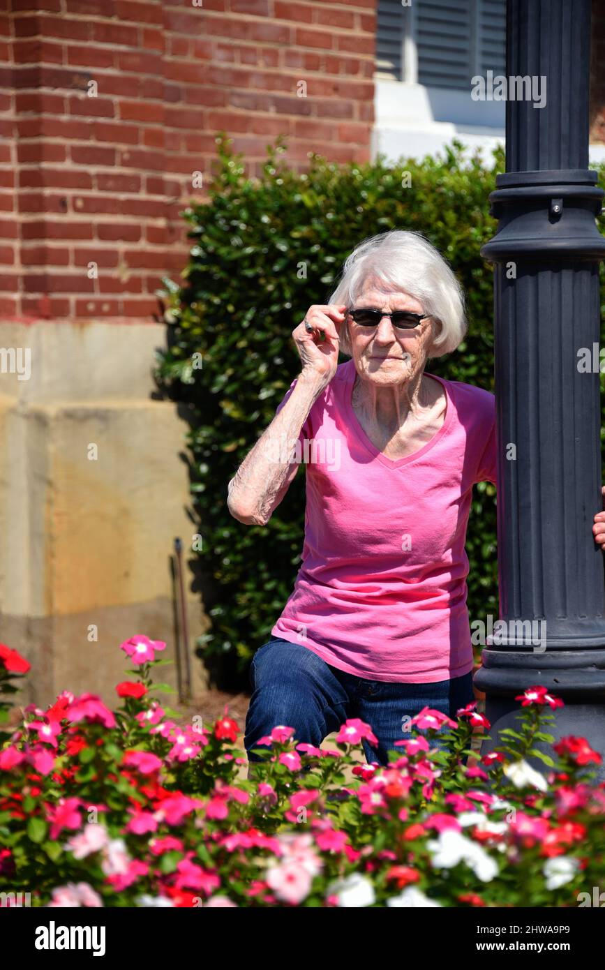 Femme âgée, vivant un siècle, ajuste ses lunettes de soleil au soleil  éclatant. Elle pourrait également examiner les changements au cours d'un  siècle et trouver le Photo Stock - Alamy
