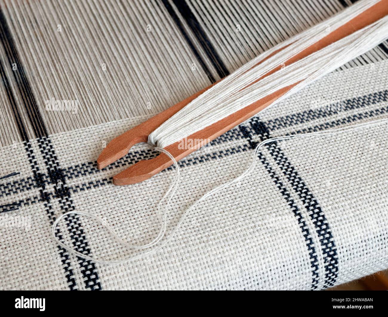 Métier à main avec tissu tissé à rayures noir et blanc et navette en bois. Production de tissage Banque D'Images