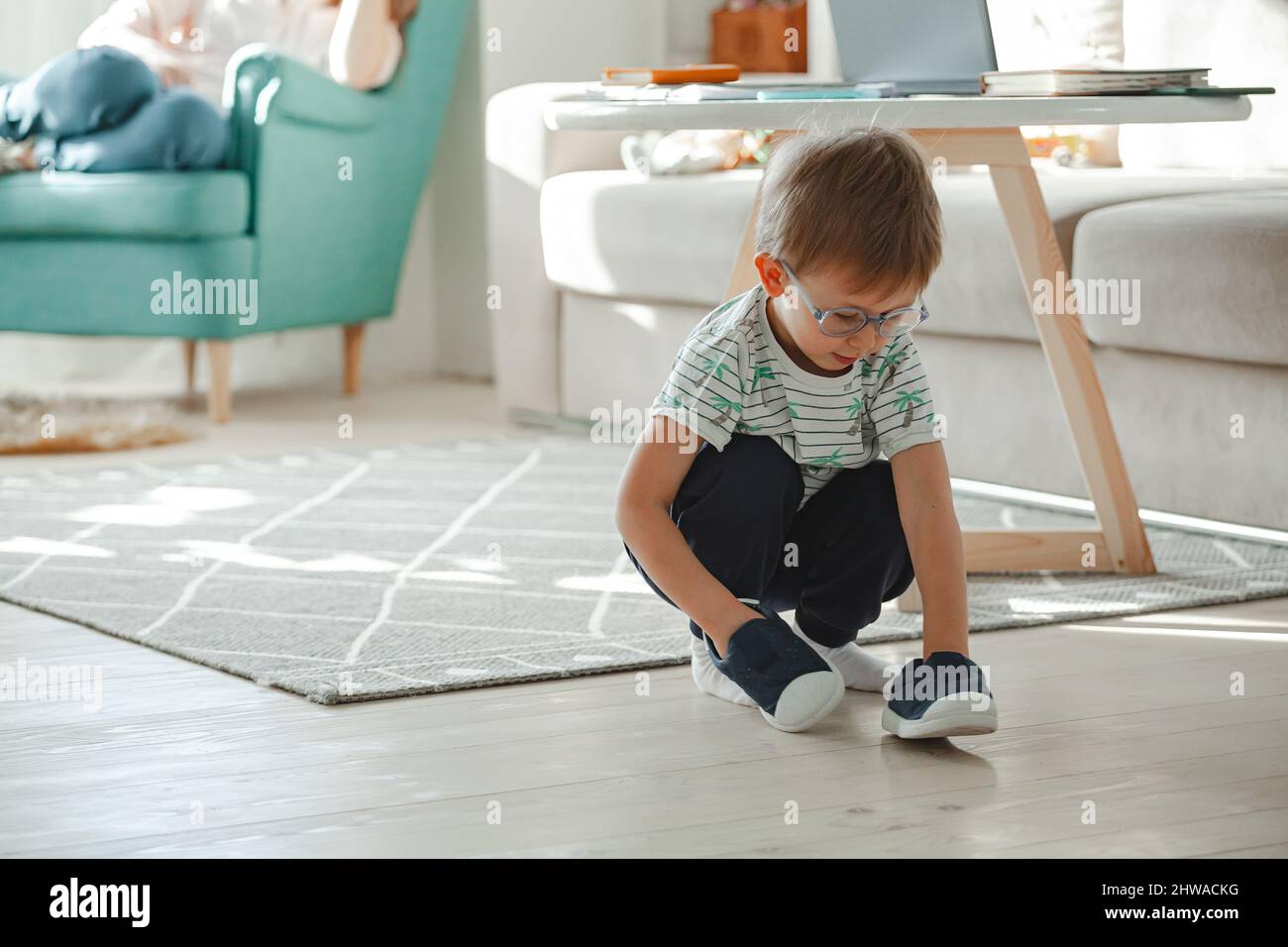 Enfant avec l'autisme dans les lunettes de jeu avec ses chaussures Banque D'Images