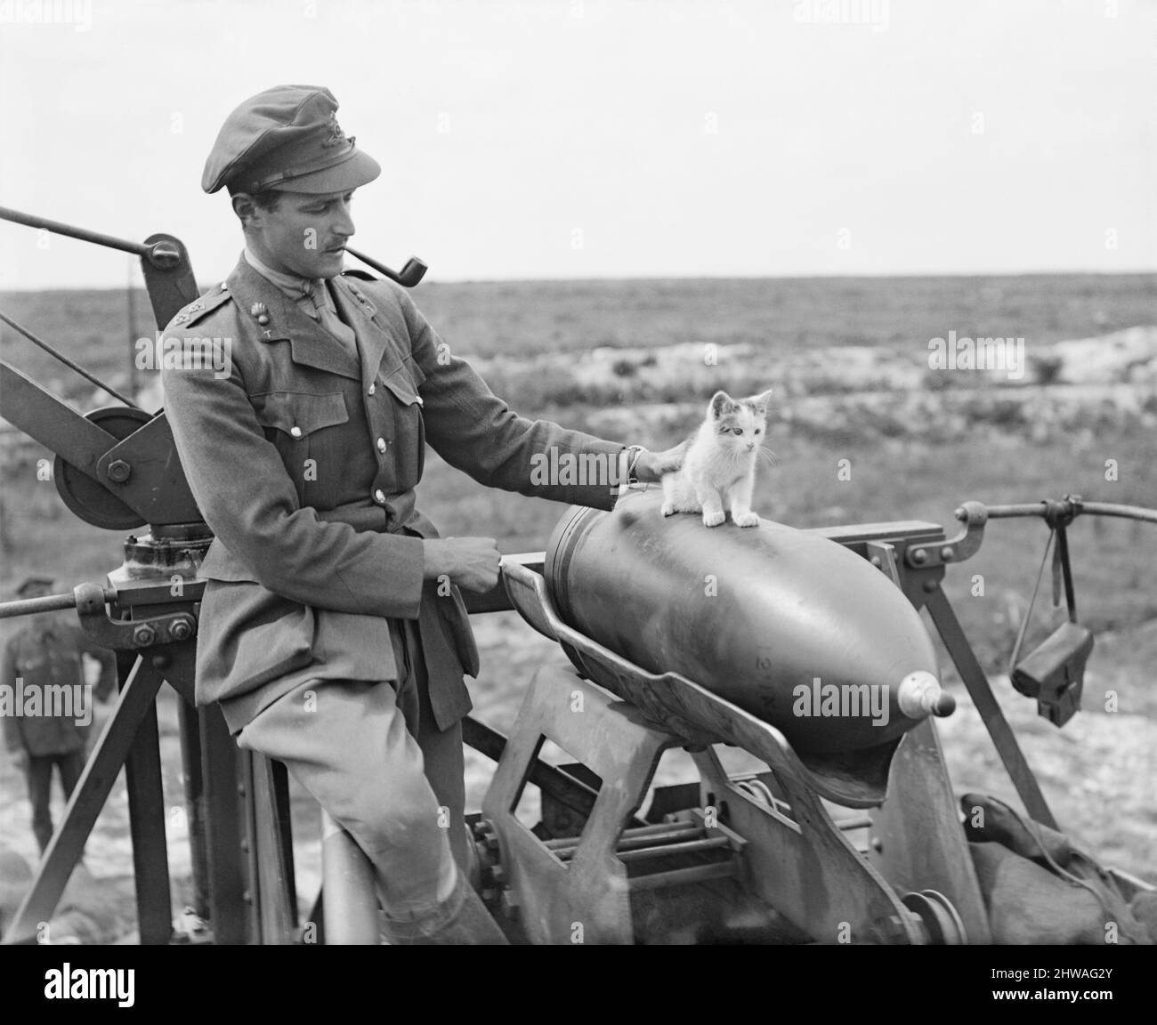 Un officier de la batterie de Siege de 444th, l'Artillerie royale de garnison (RGA), fume un tuyau alors qu'il supervise un chaton en équilibre sur une carapace de canon de 12 pouces près d'Arras, le 19 juillet 1918. Banque D'Images