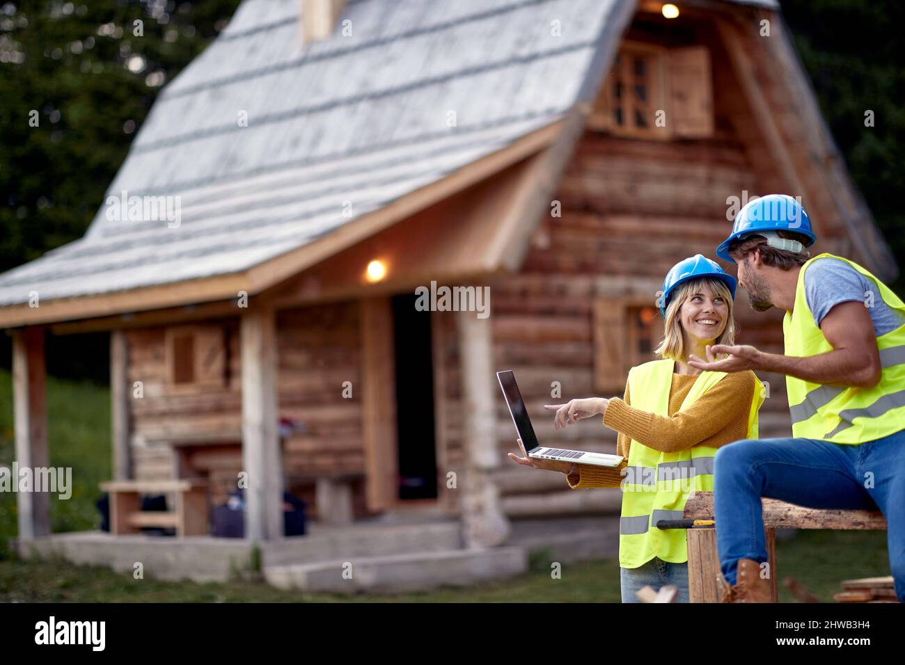 Couple de construction travaillant ensemble dans le bonheur, fille montrant à l'ordinateur portable. Bâtiment de ossature en bois. Industrie de la construction, immobilier, teamw Banque D'Images