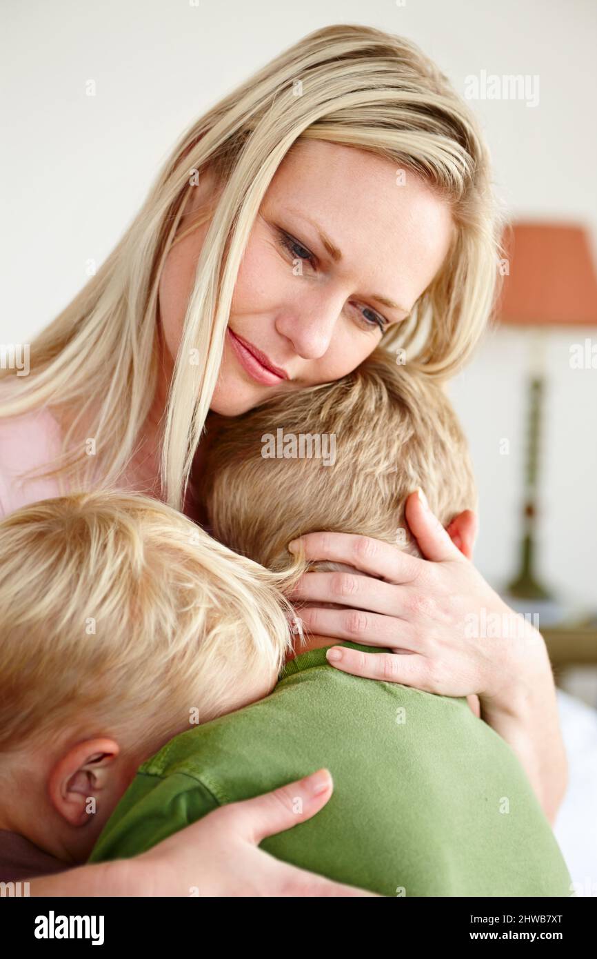 Quand mes enfants sont tristes, je suis triste. Une mère bouleversée embrassant ses deux fils. Banque D'Images