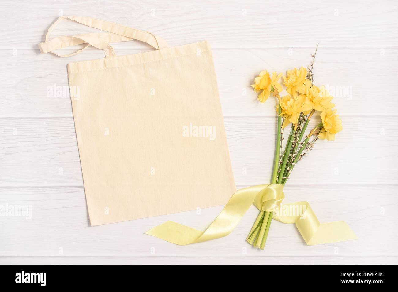 Maquette de Pâques avec sac fourre-tout blanc et bouquet jaune Banque D'Images